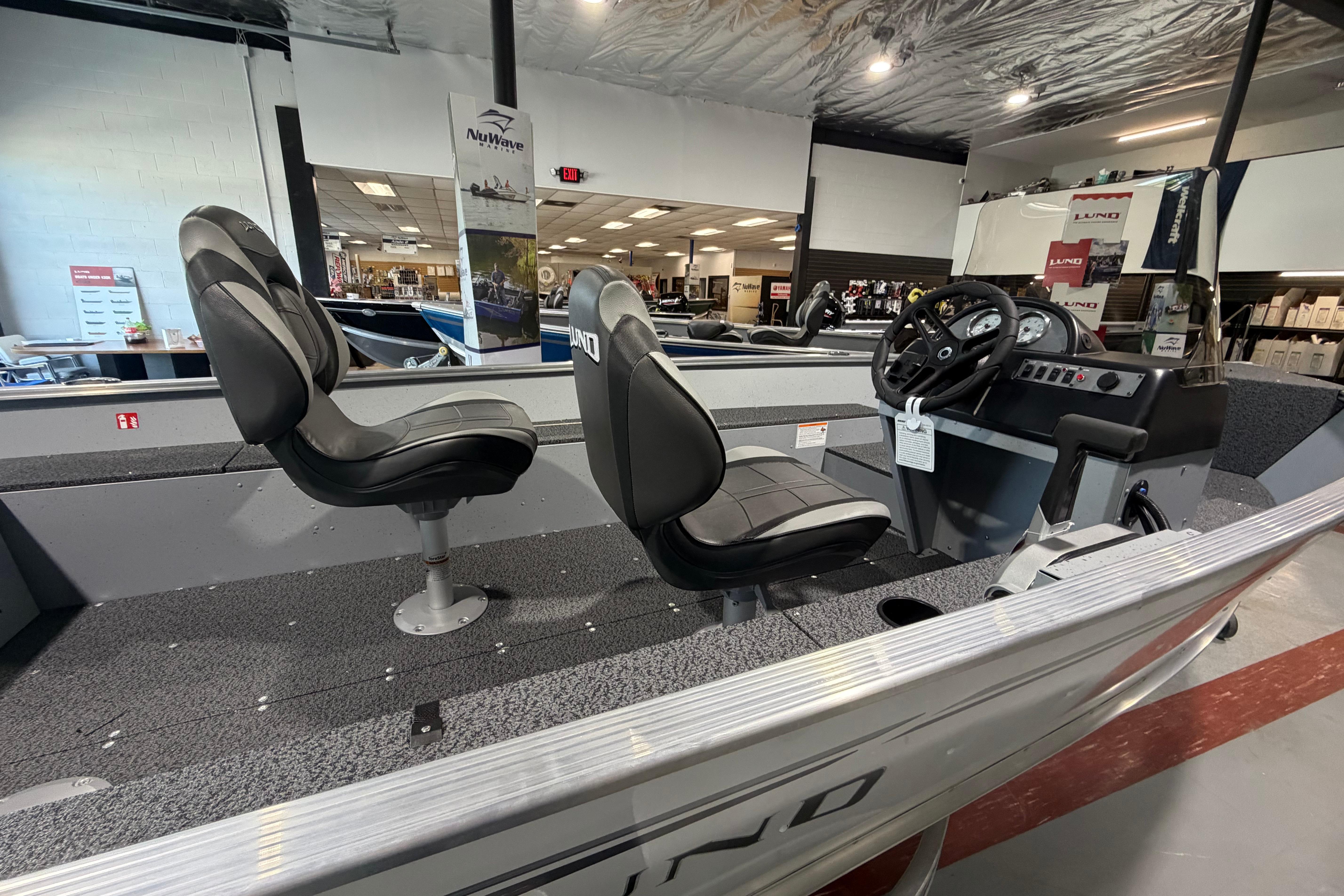 2027 Lund 1600 Fury SS boat interior with two seats and steering console in showroom.