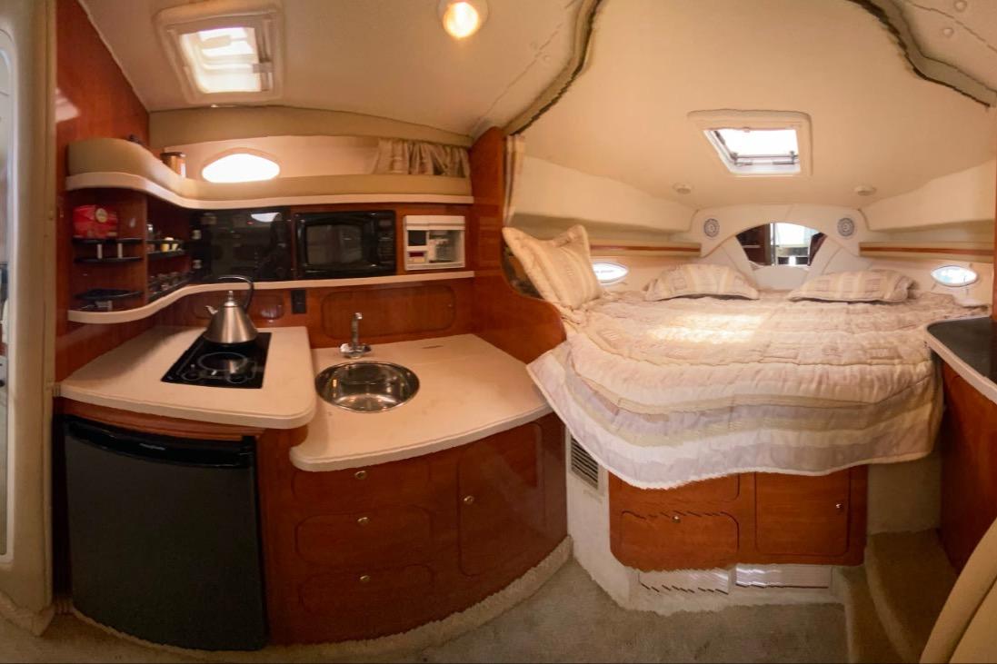 Interior of 2003 Rinker Fiesta Vee 342 boat with kitchenette and cozy sleeping area.