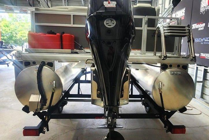 Rear view of a 2026 Sun Tracker Bass Buggy 16 DLX pontoon boat in a garage.