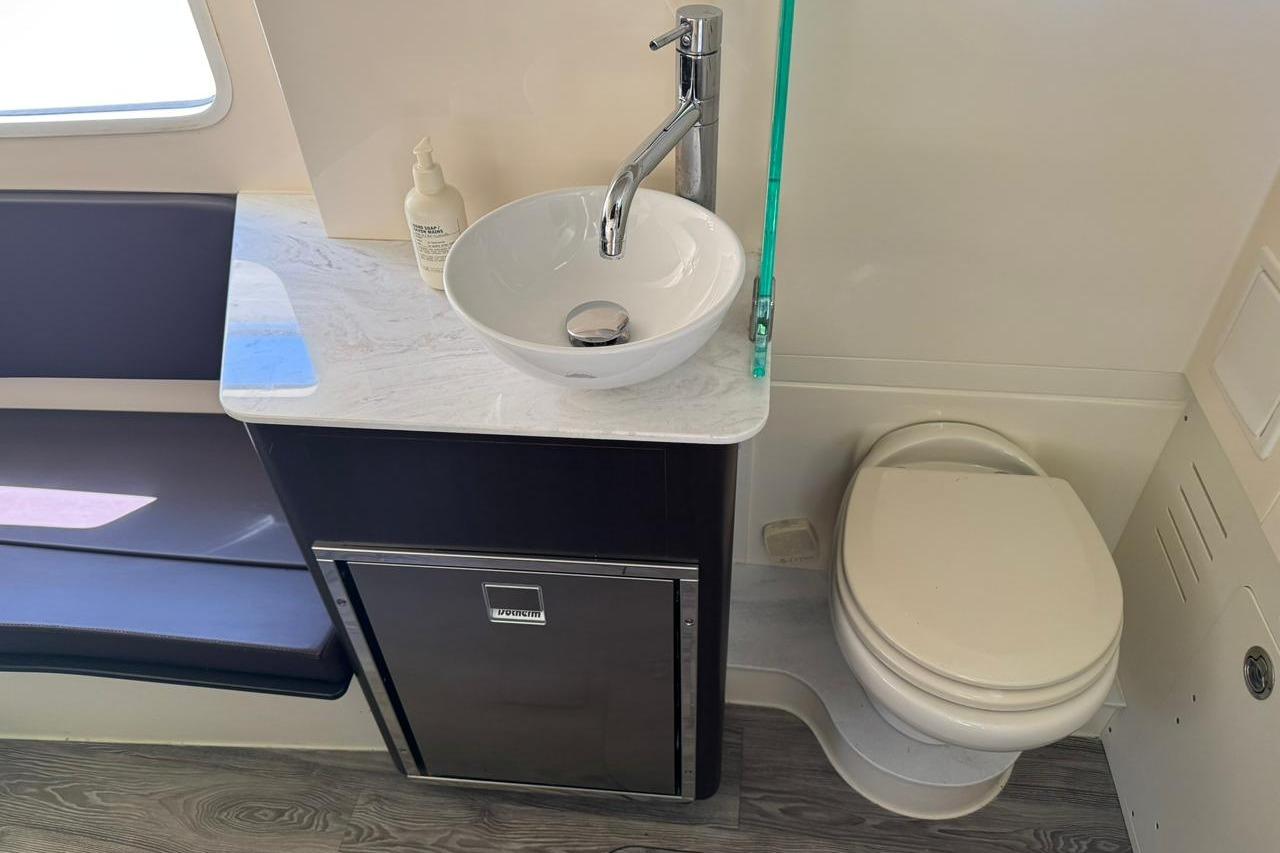 2020 Scout 355 LXF boat bathroom with sink, toilet, and storage cabinet.