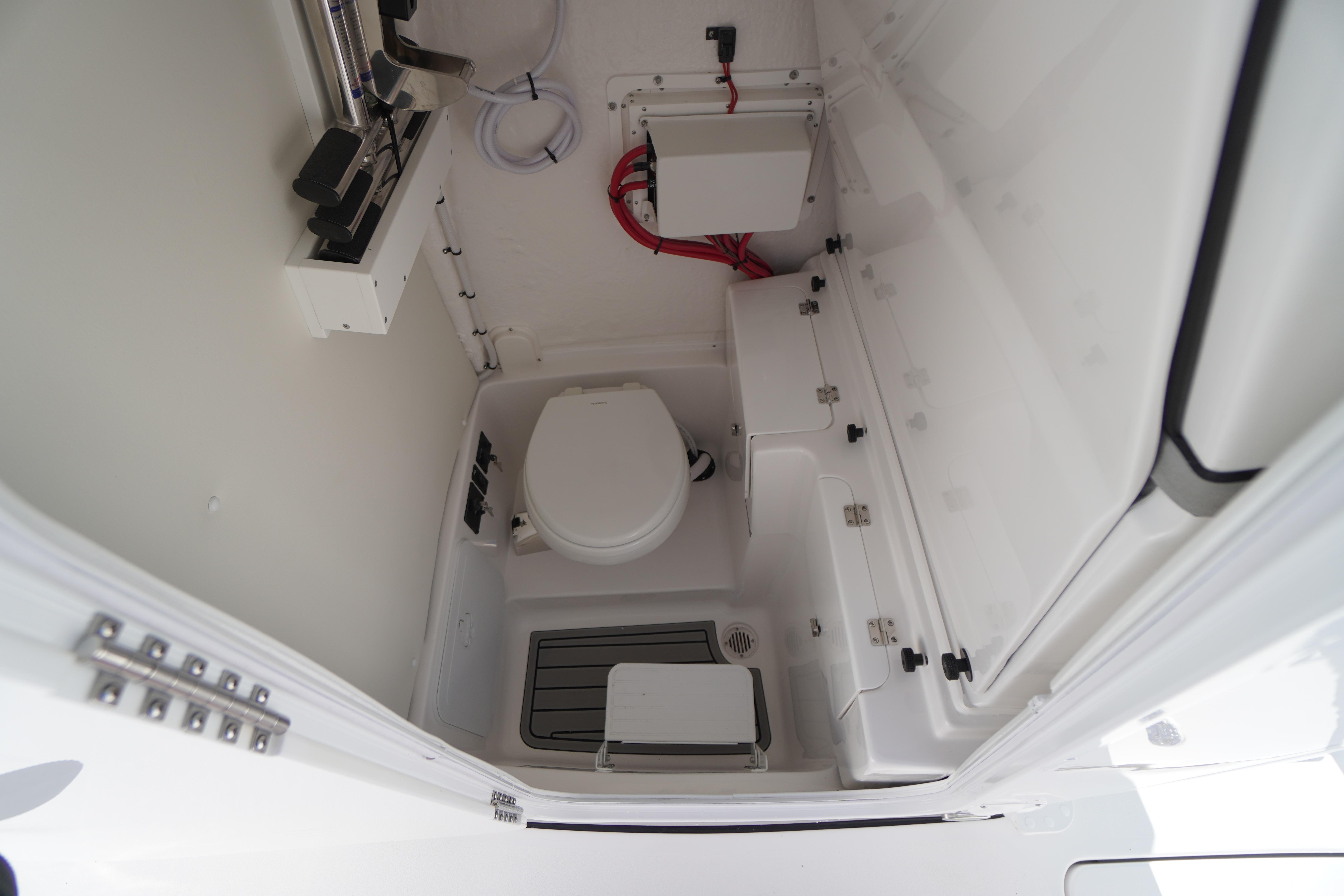 2026 Tidewater 272 LXF boat interior with compact marine toilet and storage.