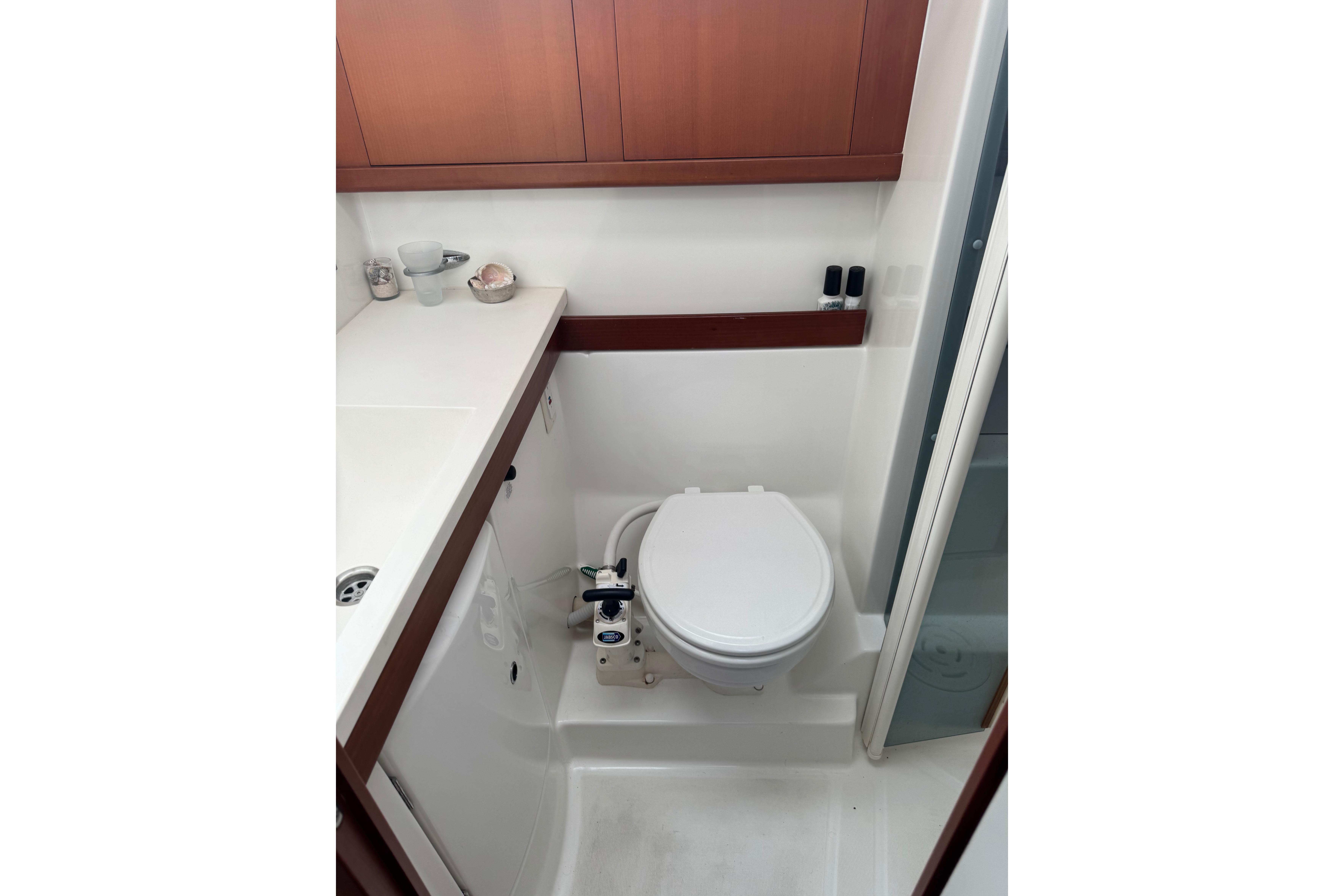 Bathroom interior of 2007 Beneteau Oceanis 49 yacht, featuring compact toilet and wooden cabinetry.