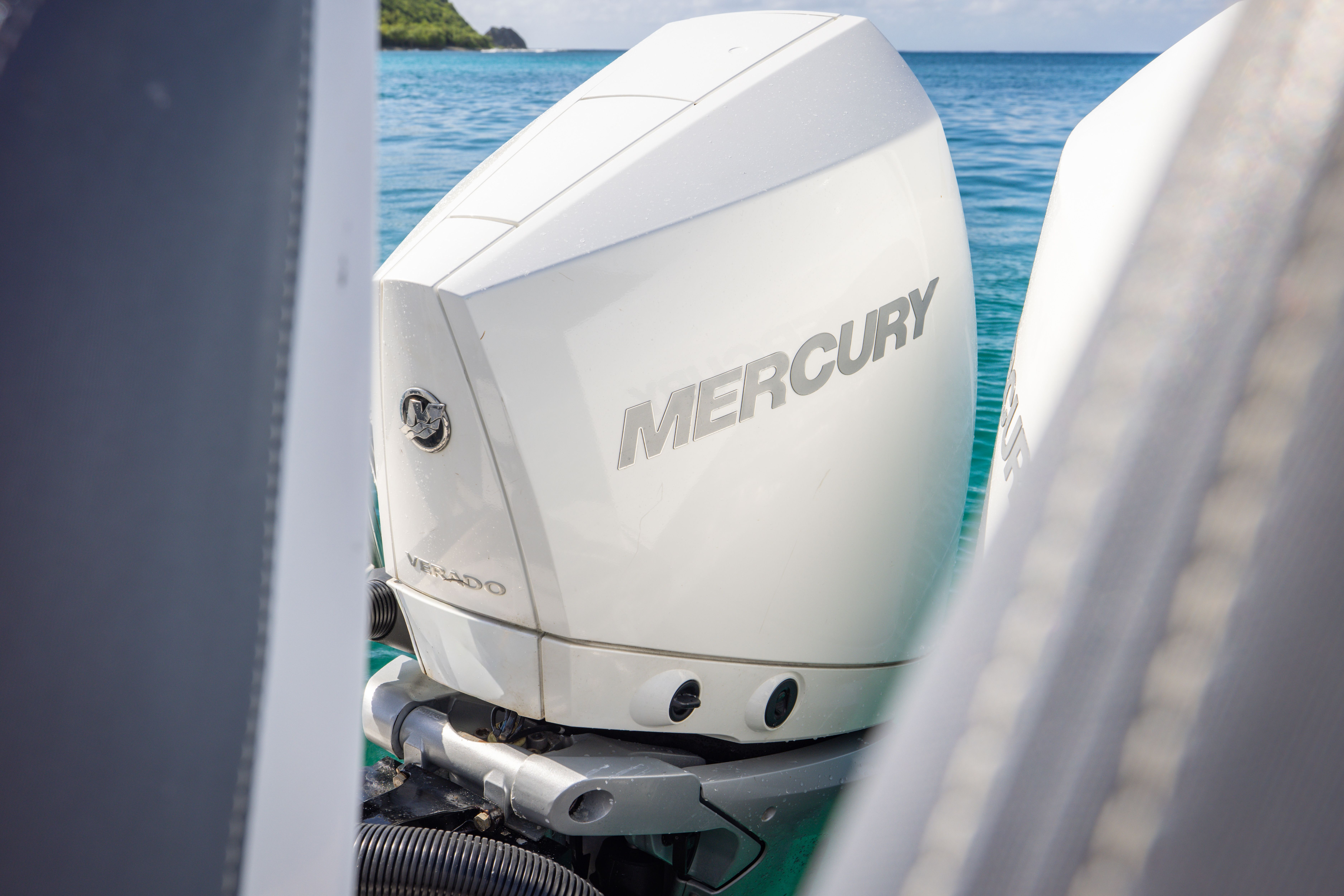 Close-up of a Mercury outboard motor on a boat in clear water.