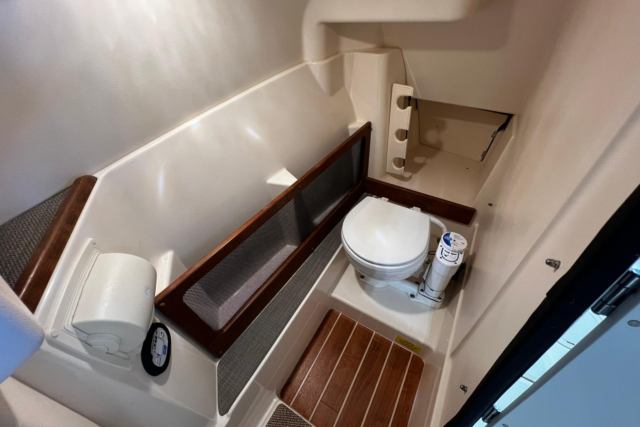 2014 Grady-White Freedom 275 boat bathroom with toilet and wooden flooring.