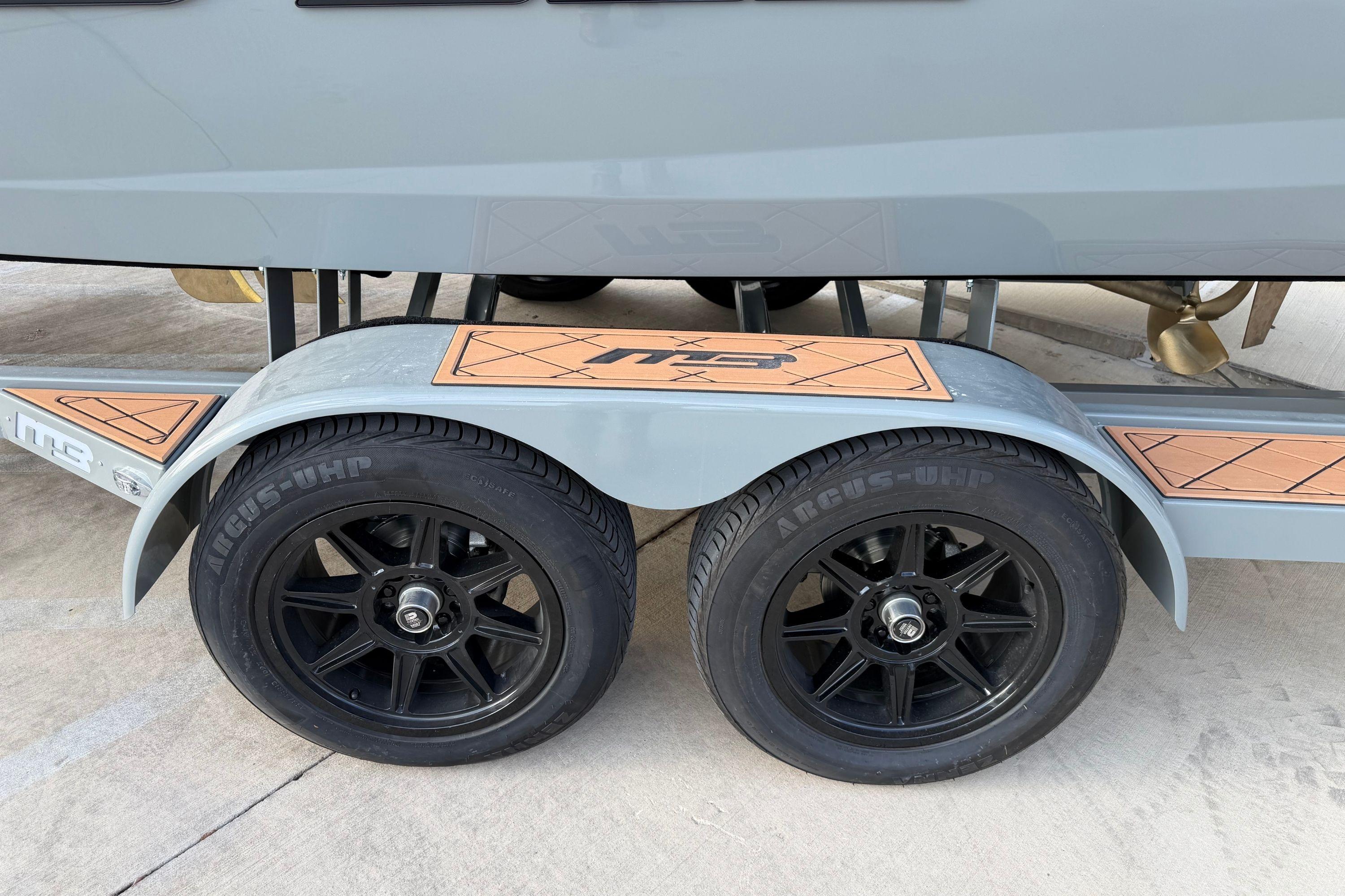 Trailer wheels of 2026 MB B52 21 Alpha boat, featuring black rims and Argus-UHP tires.