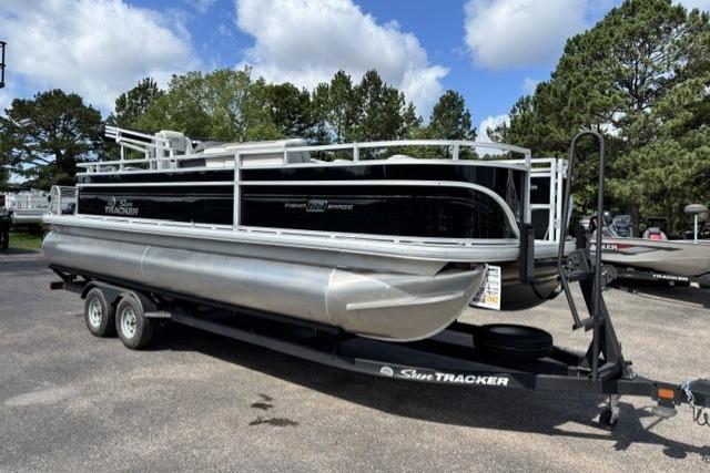 2026 Sun Tracker Fishin' Barge 22 DLX pontoon boat on trailer, parked outdoors.