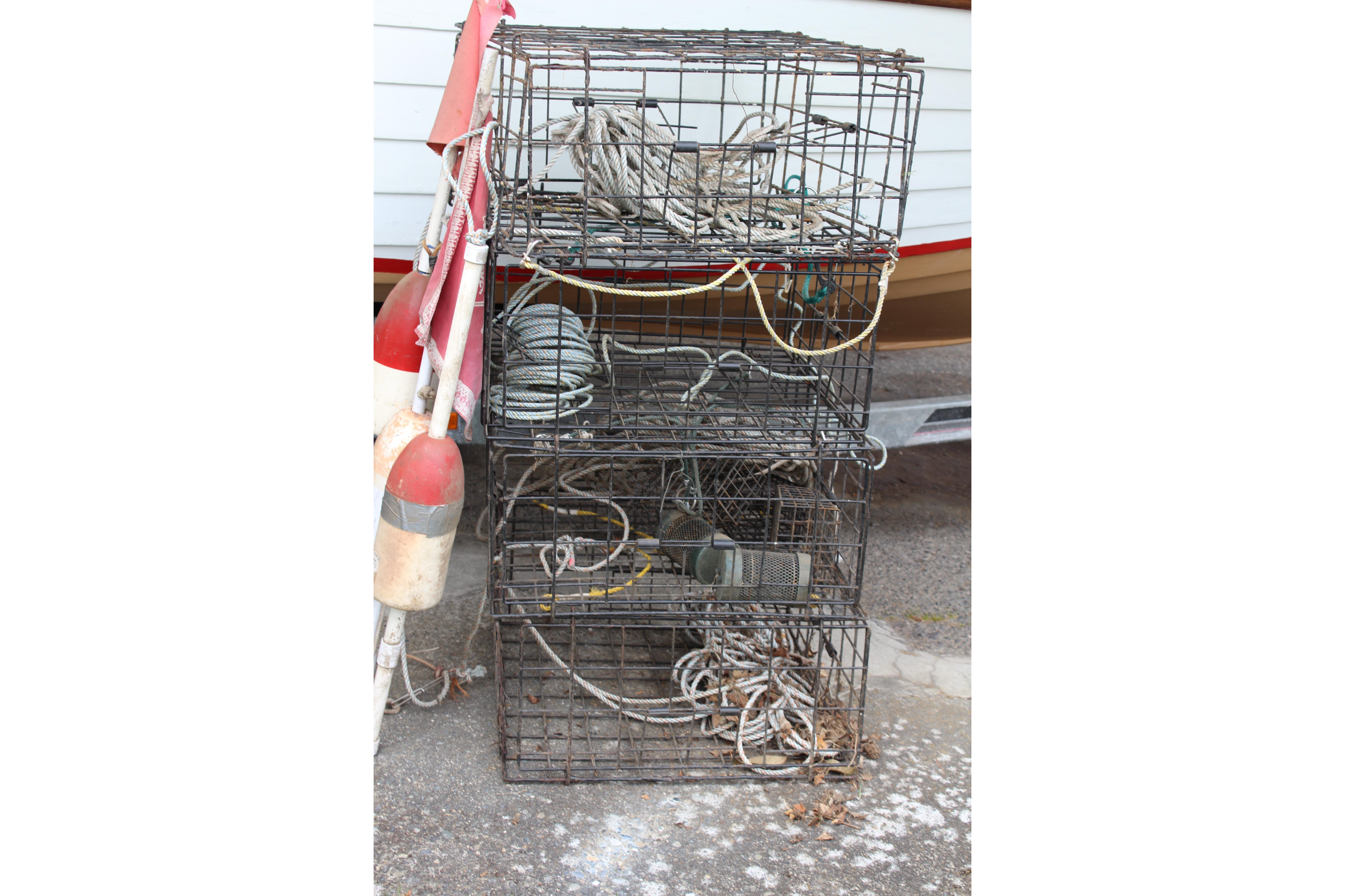 Stacked fishing traps with ropes and buoys beside a 1960 Thompson fishing boat.