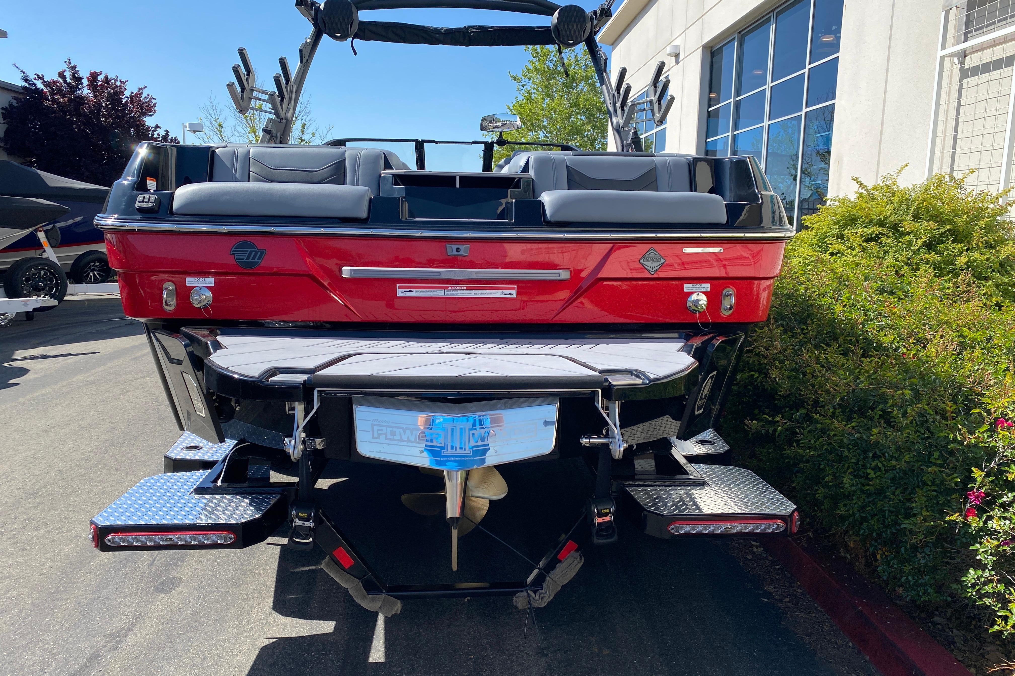 2025 Malibu Wakesetter 23 LSV boat, rear view, red exterior, parked outdoors.