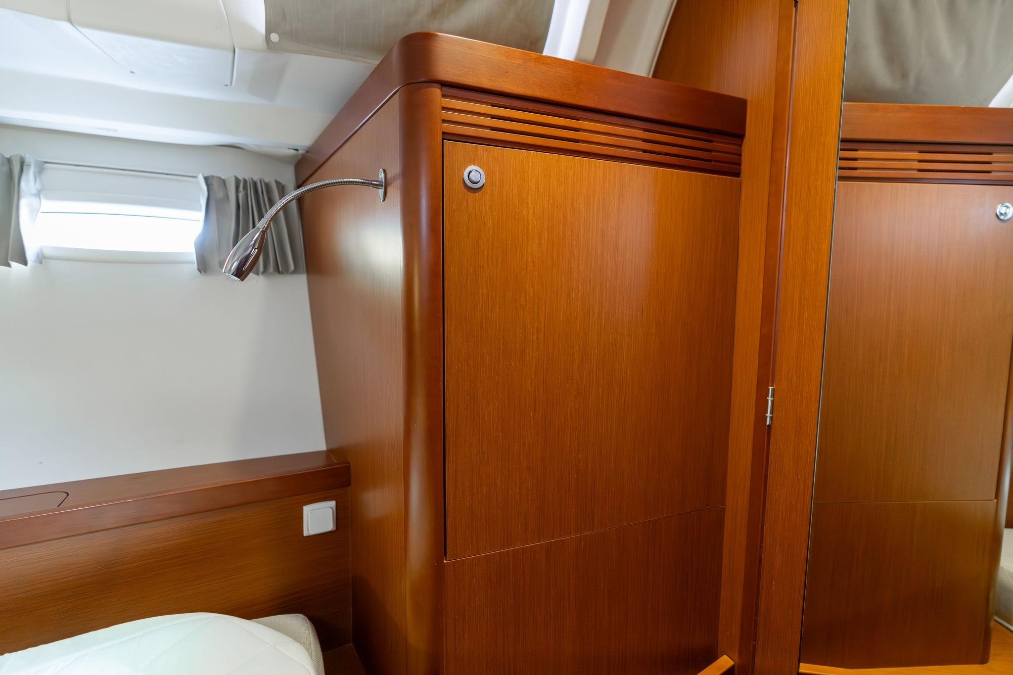 Interior cabin of 2013 Beneteau Oceanis 50 yacht with wooden finish and reading light.