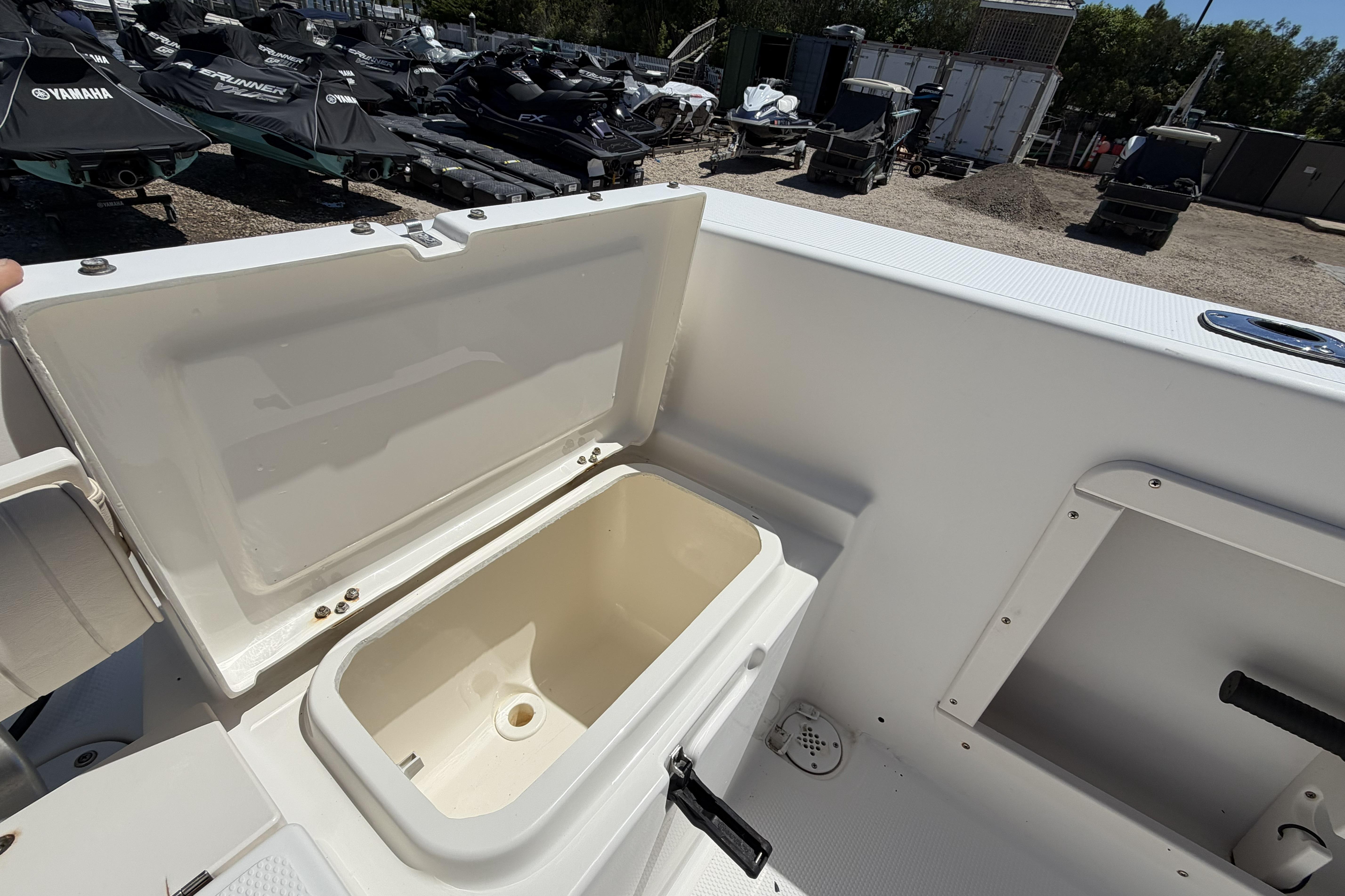 Open storage compartment on a 2006 Mako 212 Center Console boat, with jet skis in the background.