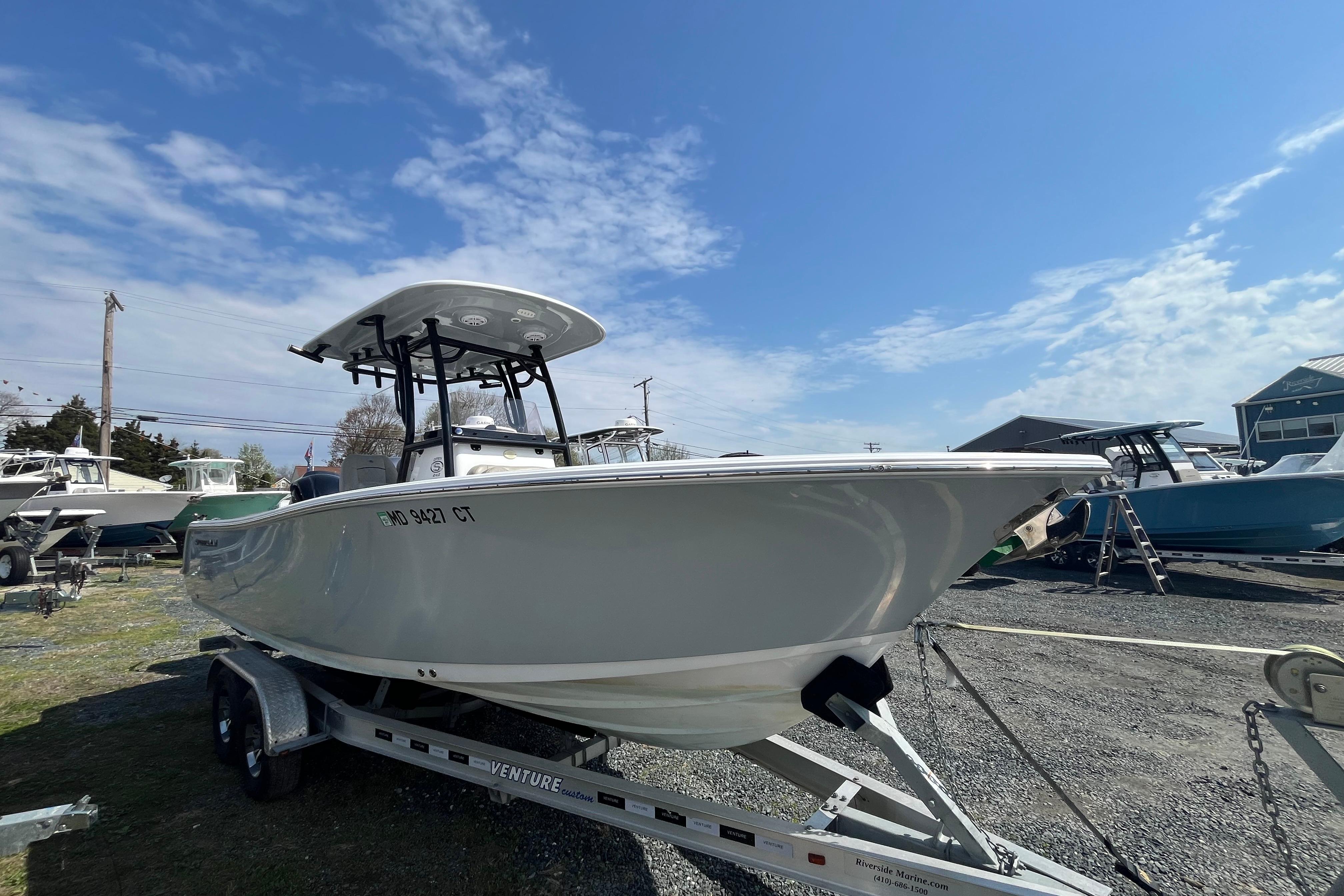 2022 Sportsman Open 242 Center Console boat on trailer under blue sky.