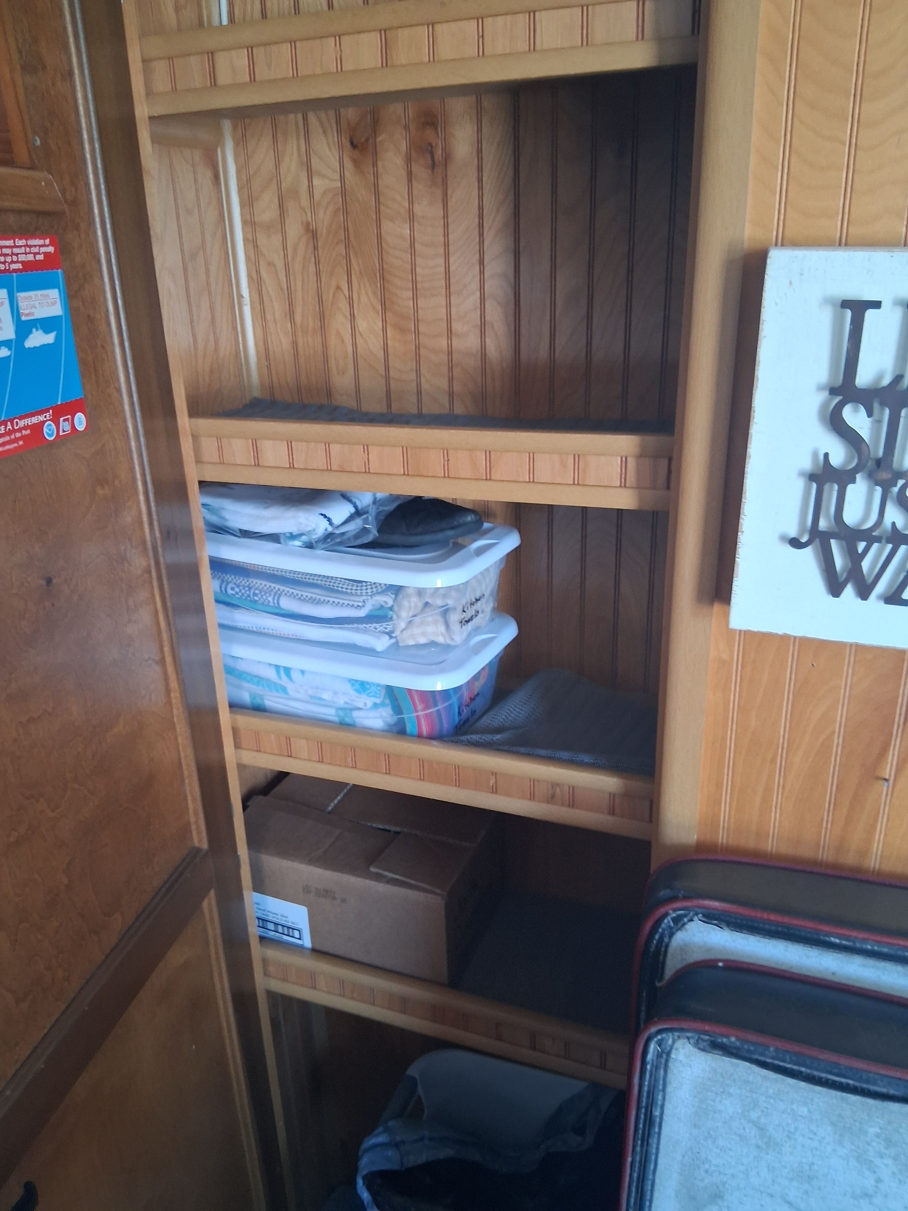 A wooden shelf with plastic containers and boxes inside a boat.
