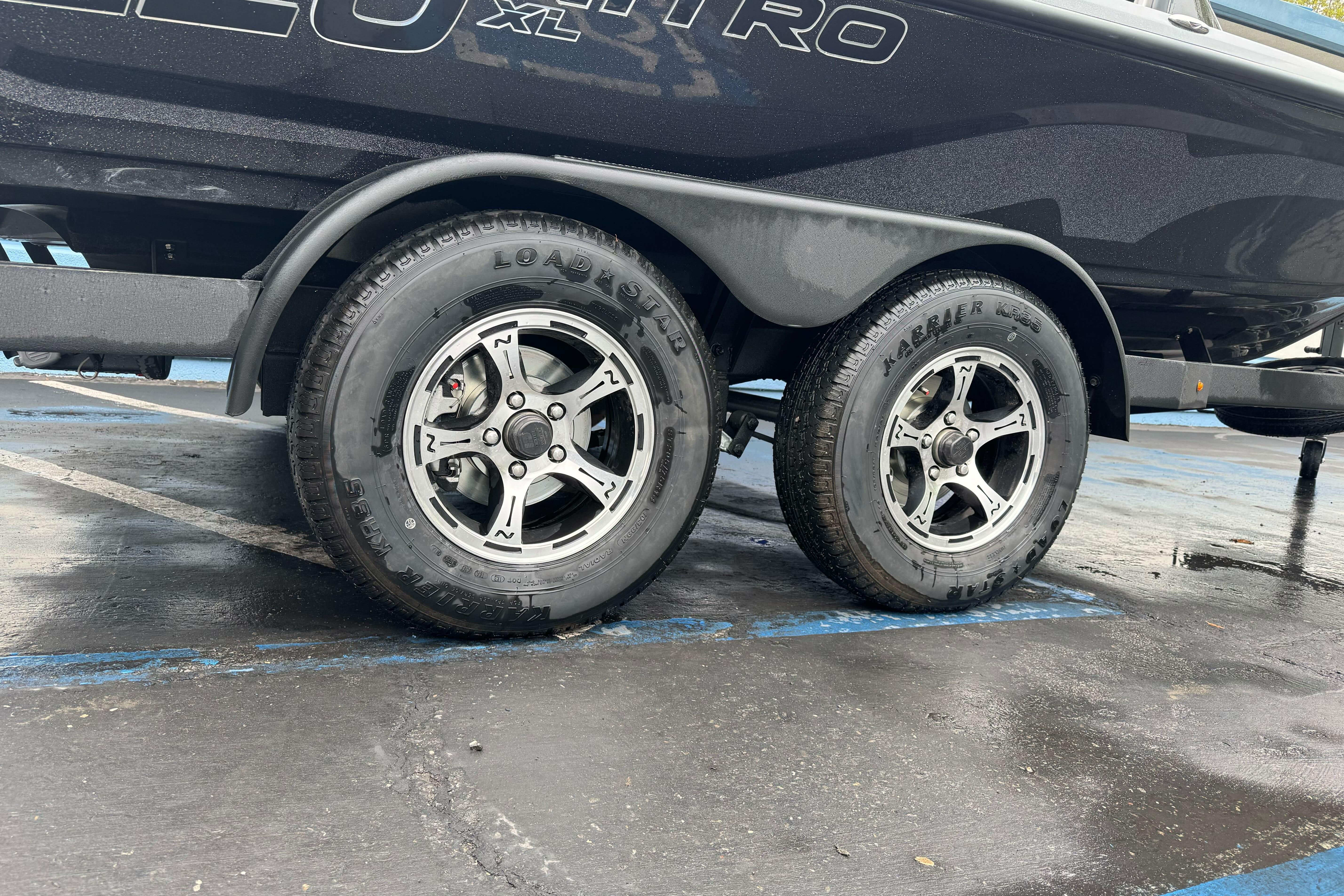 Trailer wheels of a 2026 Nitro Z20 XL Pro boat on wet pavement.