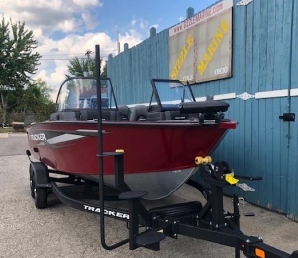 2025 Tracker Targa V-18 Combo boat on trailer, parked near blue fence.