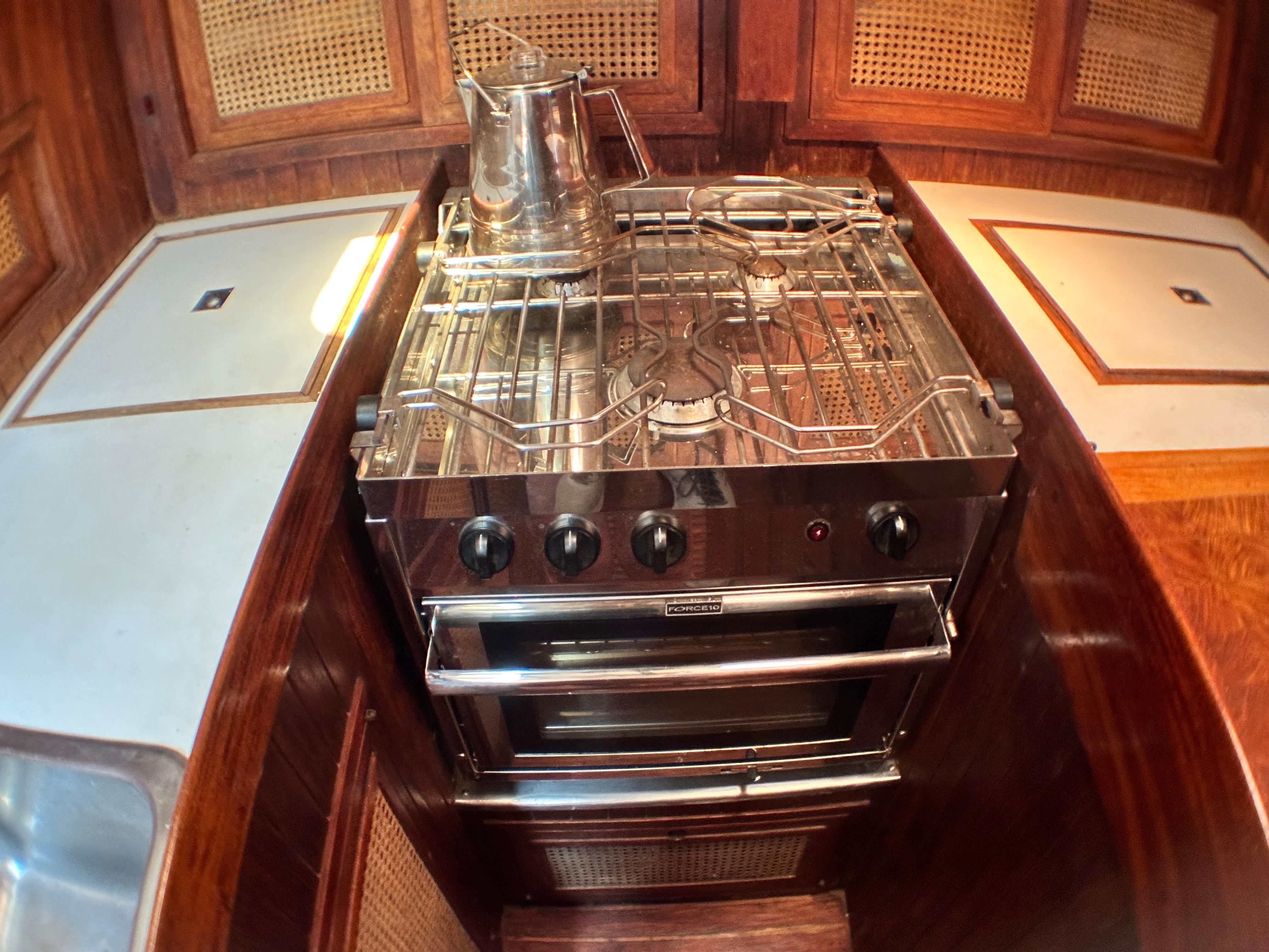 Vintage 1982 Pan Oceanic 43 yacht kitchen with stainless steel stove and wooden cabinetry.