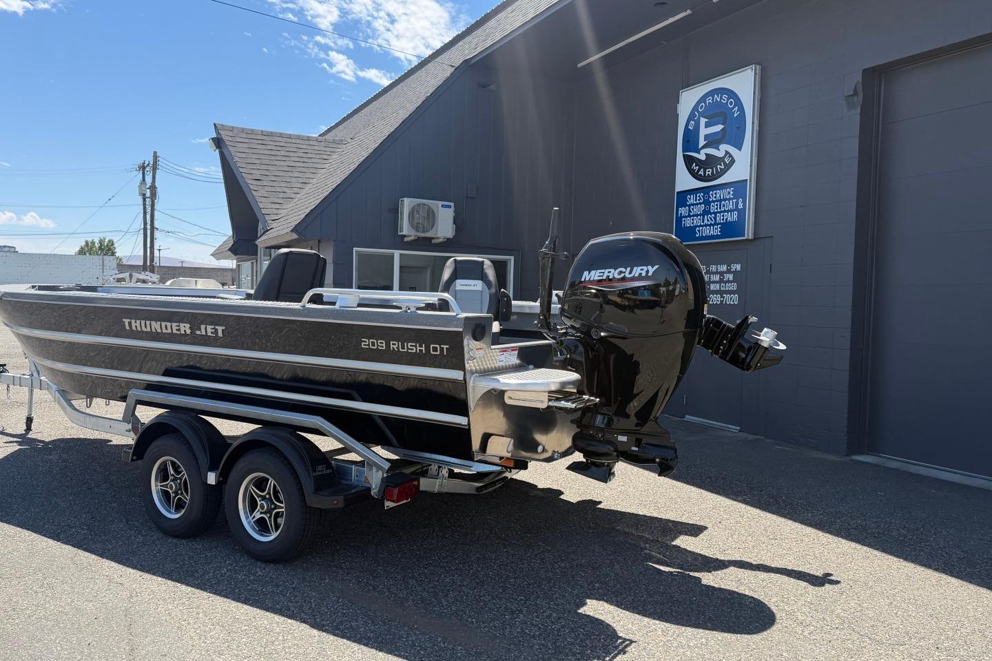 2026 Thunder Jet 209 Rush OT boat with Mercury engine on trailer outside marine shop.