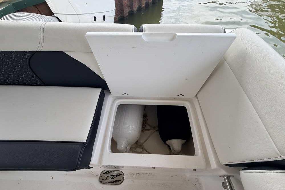 2024 Tidewater 232 LXF boat seat storage compartment open, revealing interior space.