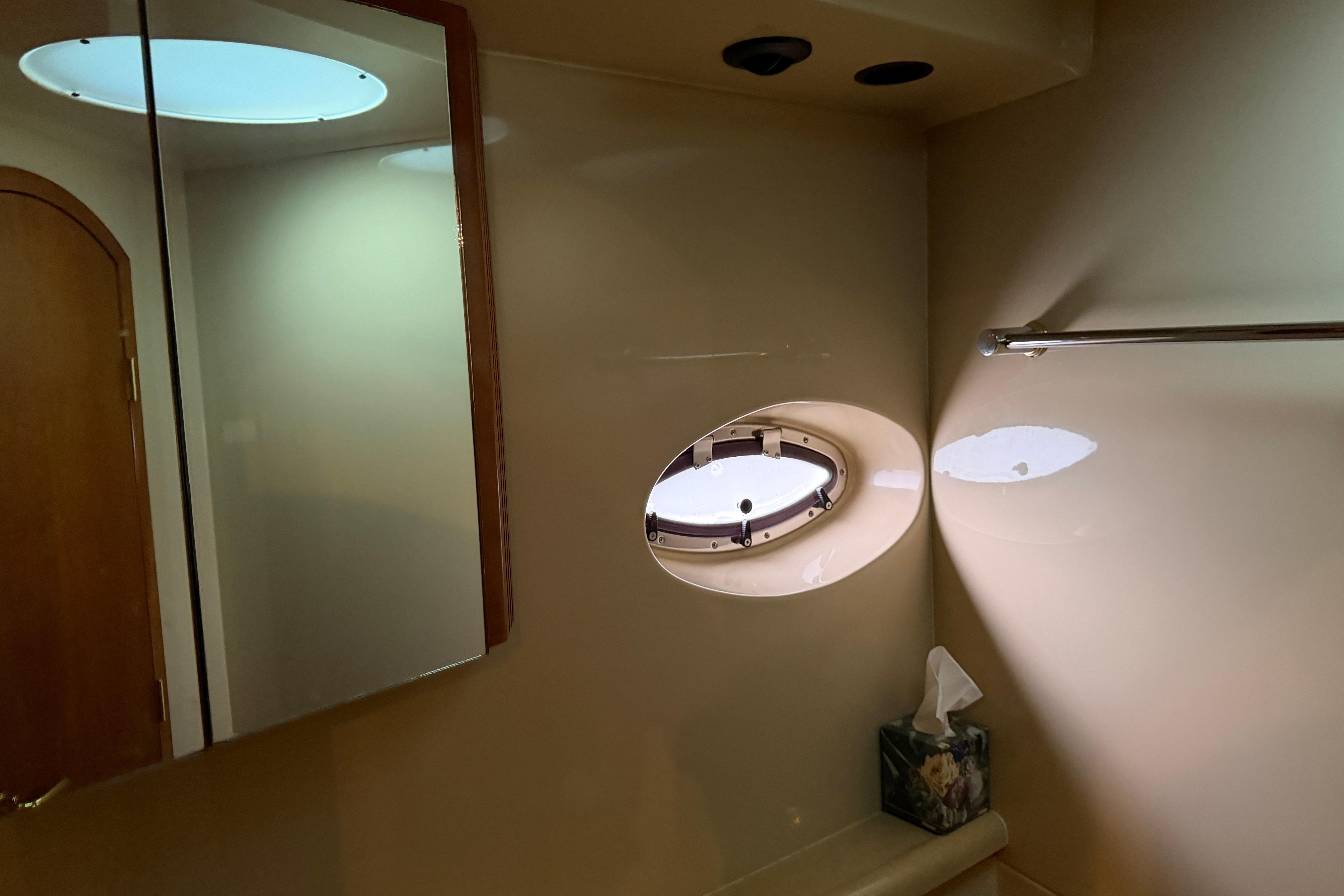 Bathroom interior of 2003 Cruisers Yachts 405 Express Motoryacht with porthole and mirror.