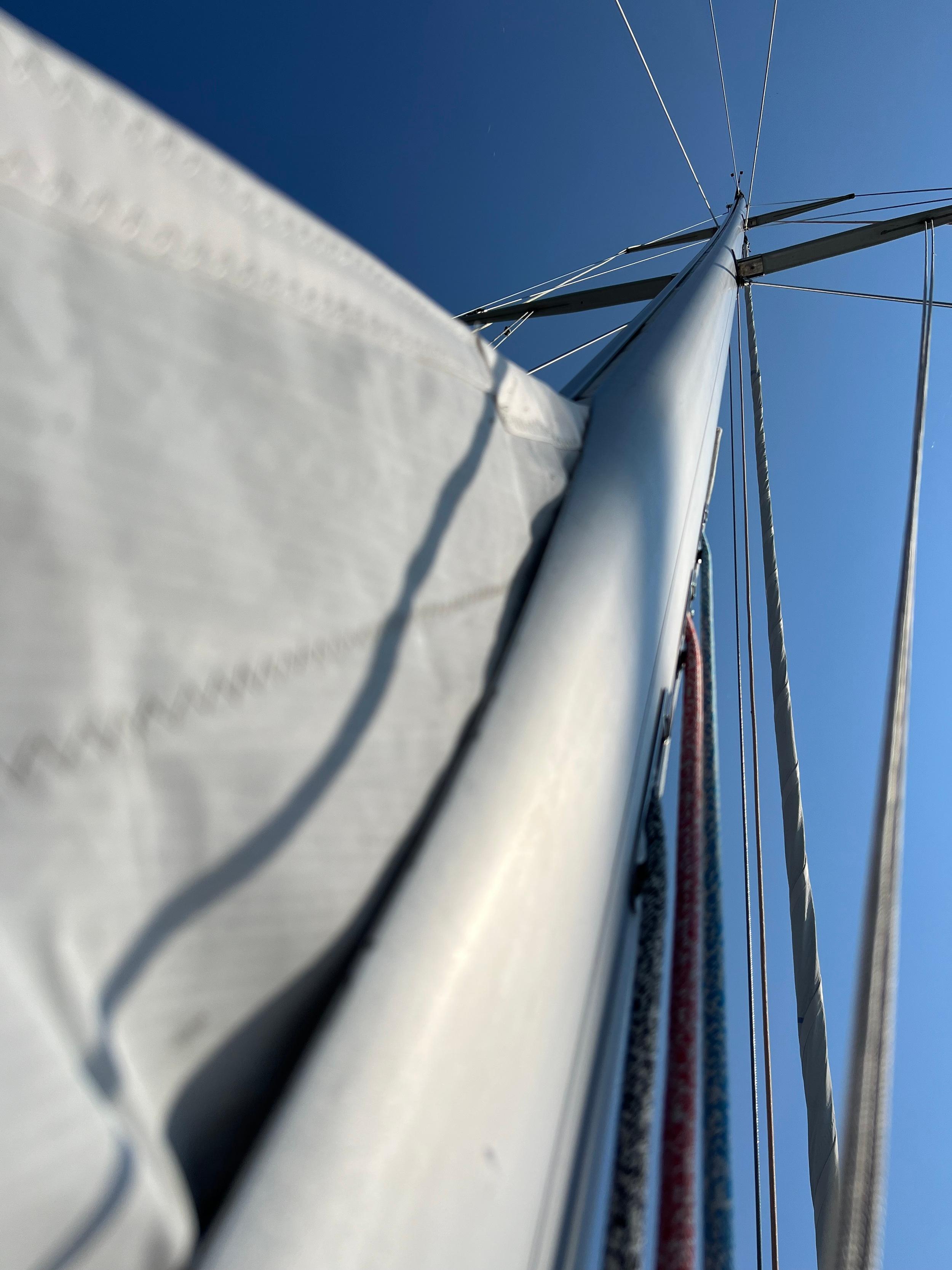 Close-up of a Jonmeri 40 sailboat mast and sail against a clear blue sky.