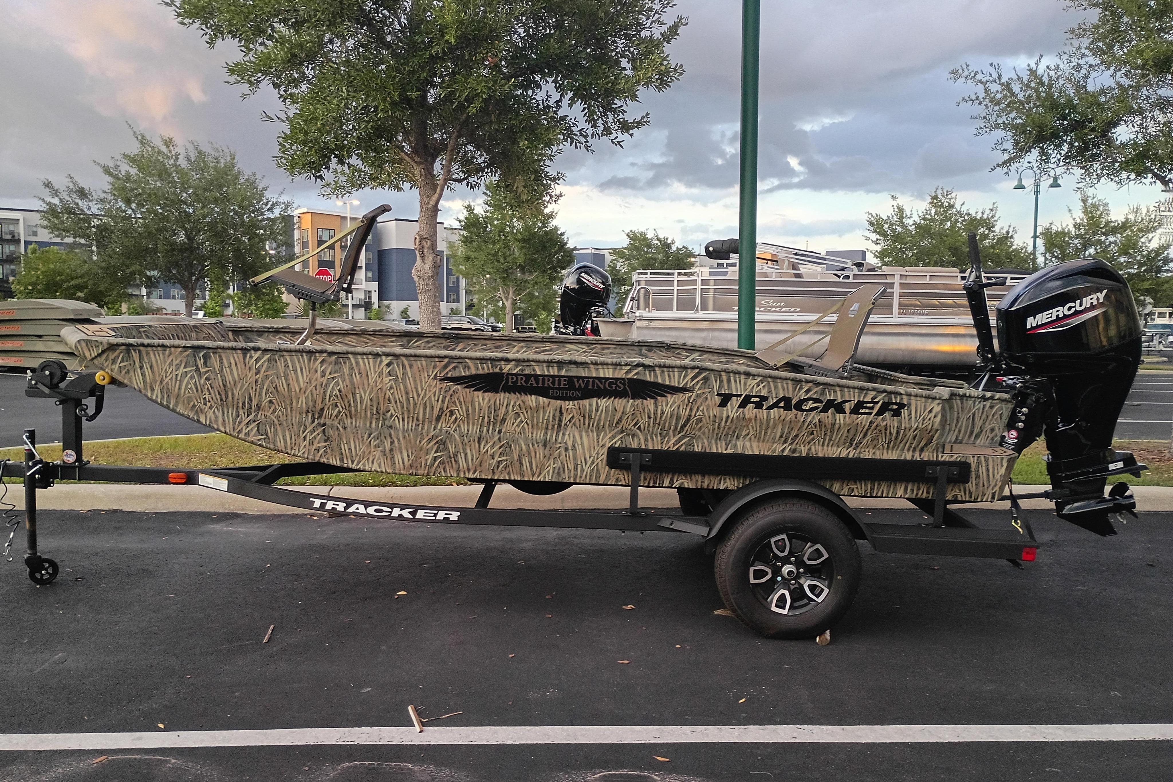 2026 Tracker Grizzly 1650 T Prairie Wings Edition boat on trailer, camo design, parked outdoors.