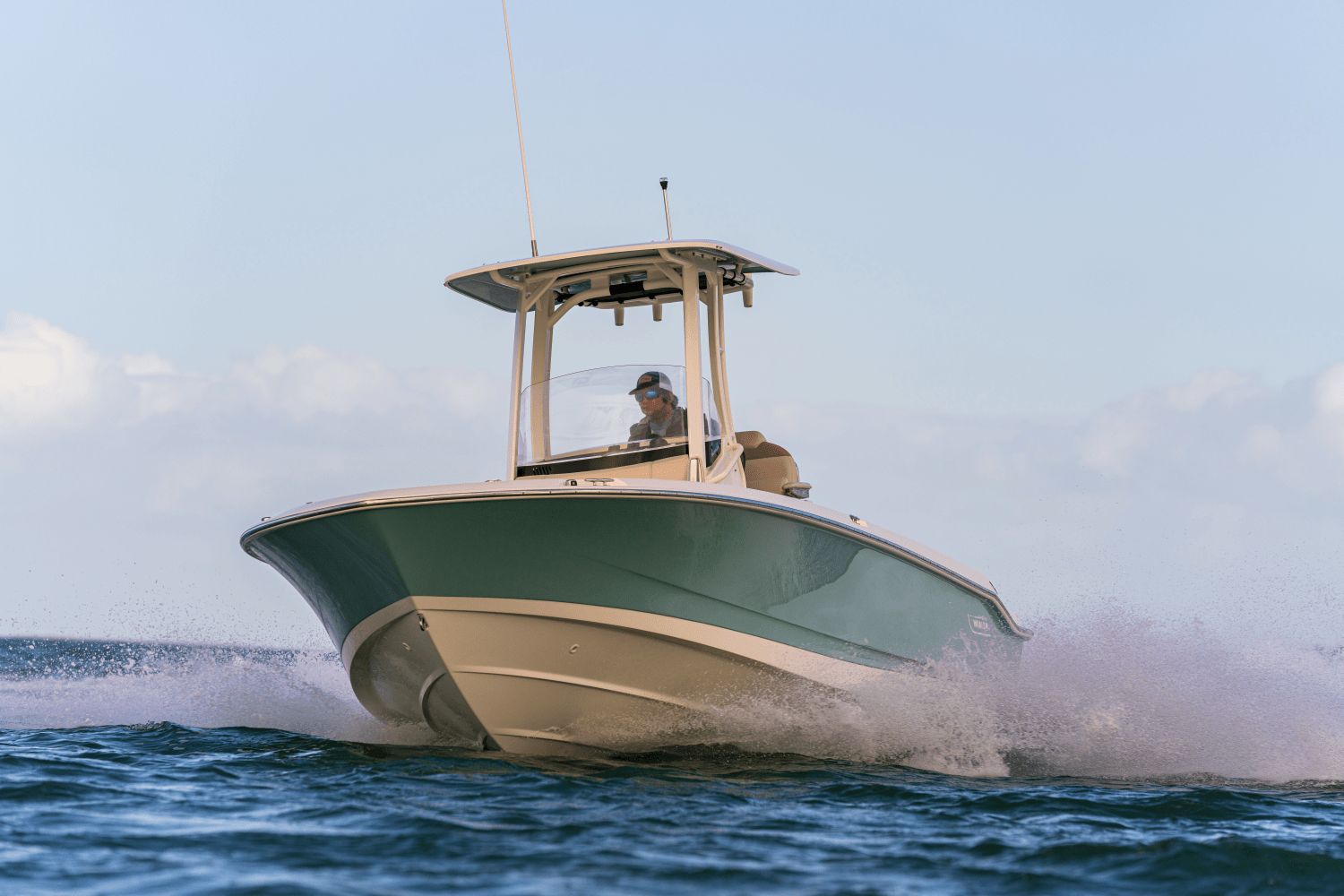 A Boston Whaler 25DA boat speeds across the water, surrounded by splashing waves.