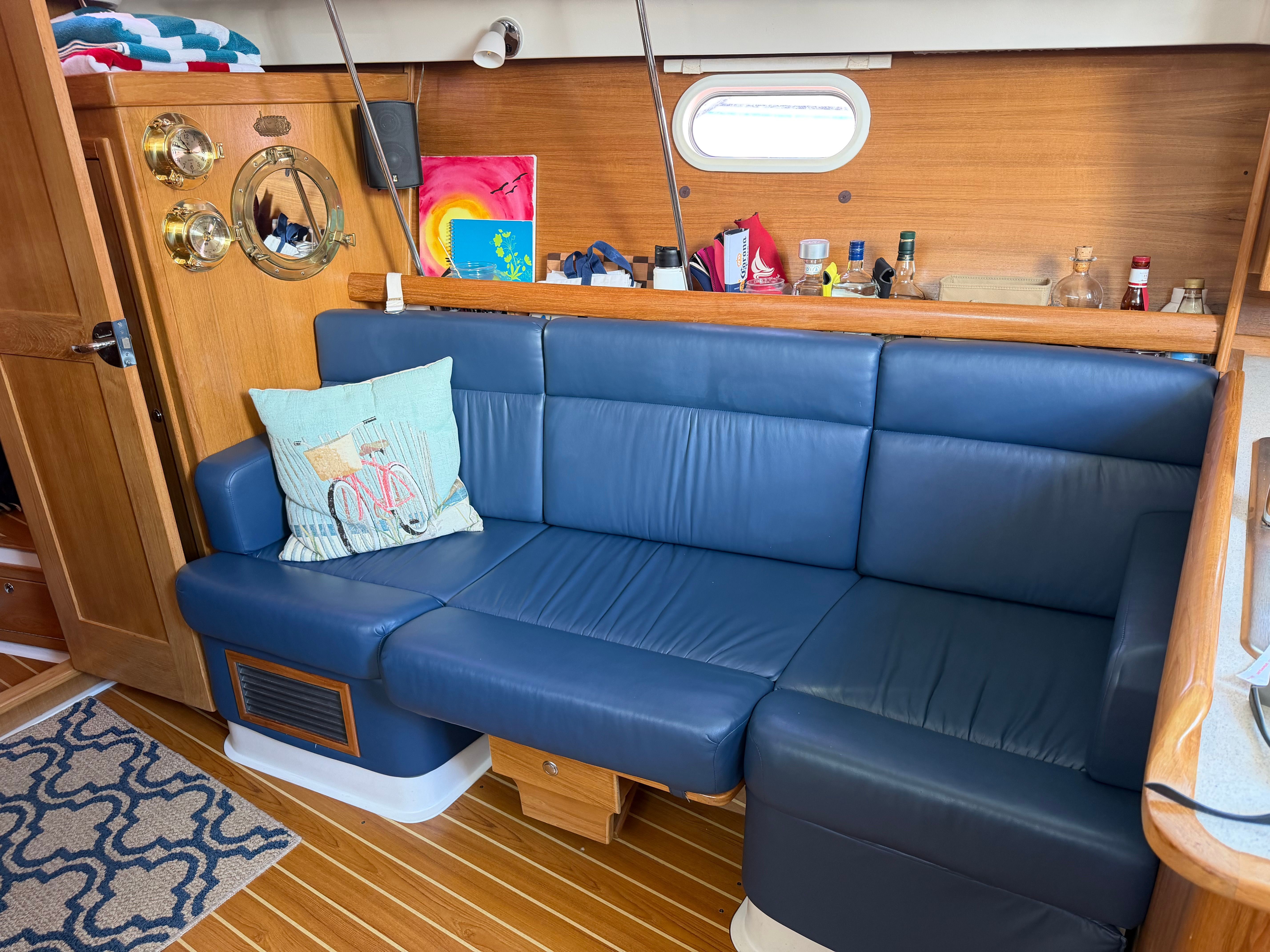 Interior of a Catalina 350 with a blue leather couch and wooden walls.