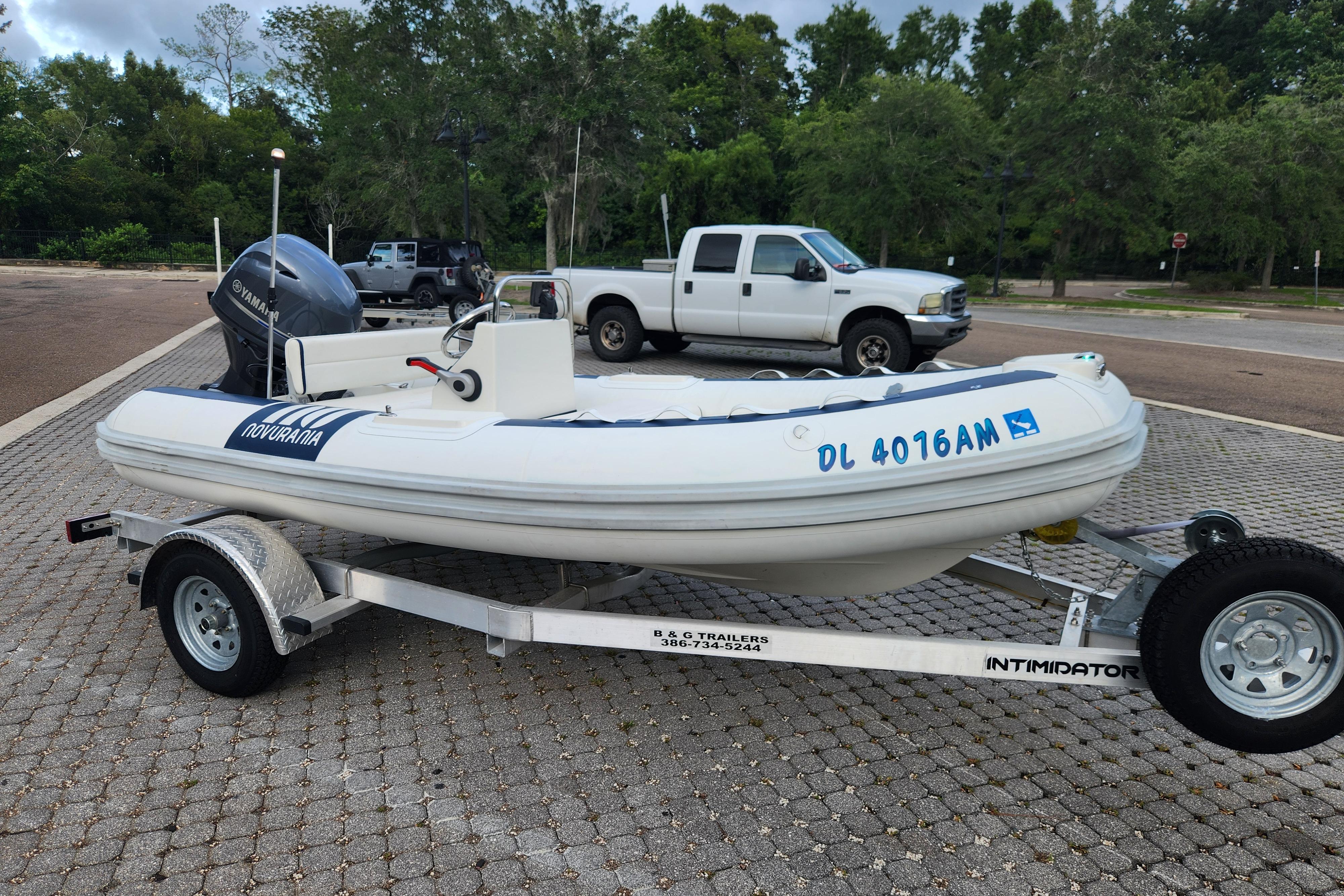 2019 Novurania DL 400 boat on trailer, parked in a lot with trees in background.
