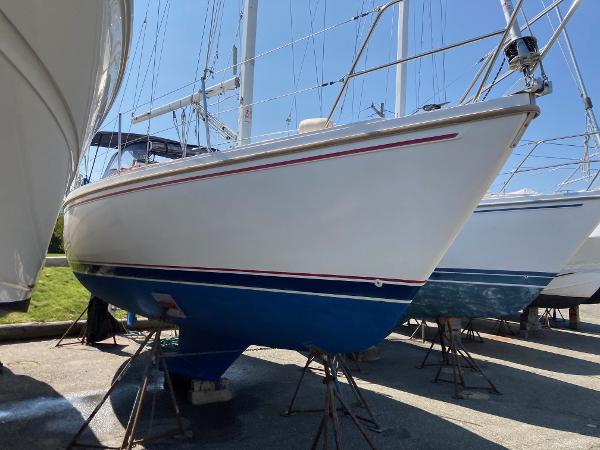 1989 Catalina 30 sailboat on stands, white hull with blue bottom, in a marina.