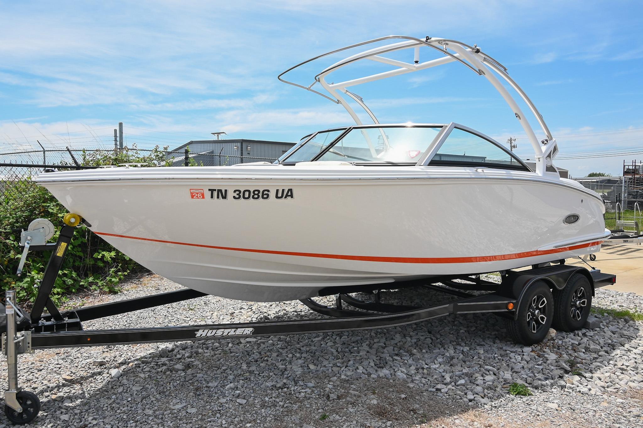 2022 Cobalt CS22 boat on trailer, white with orange stripe, parked outdoors.