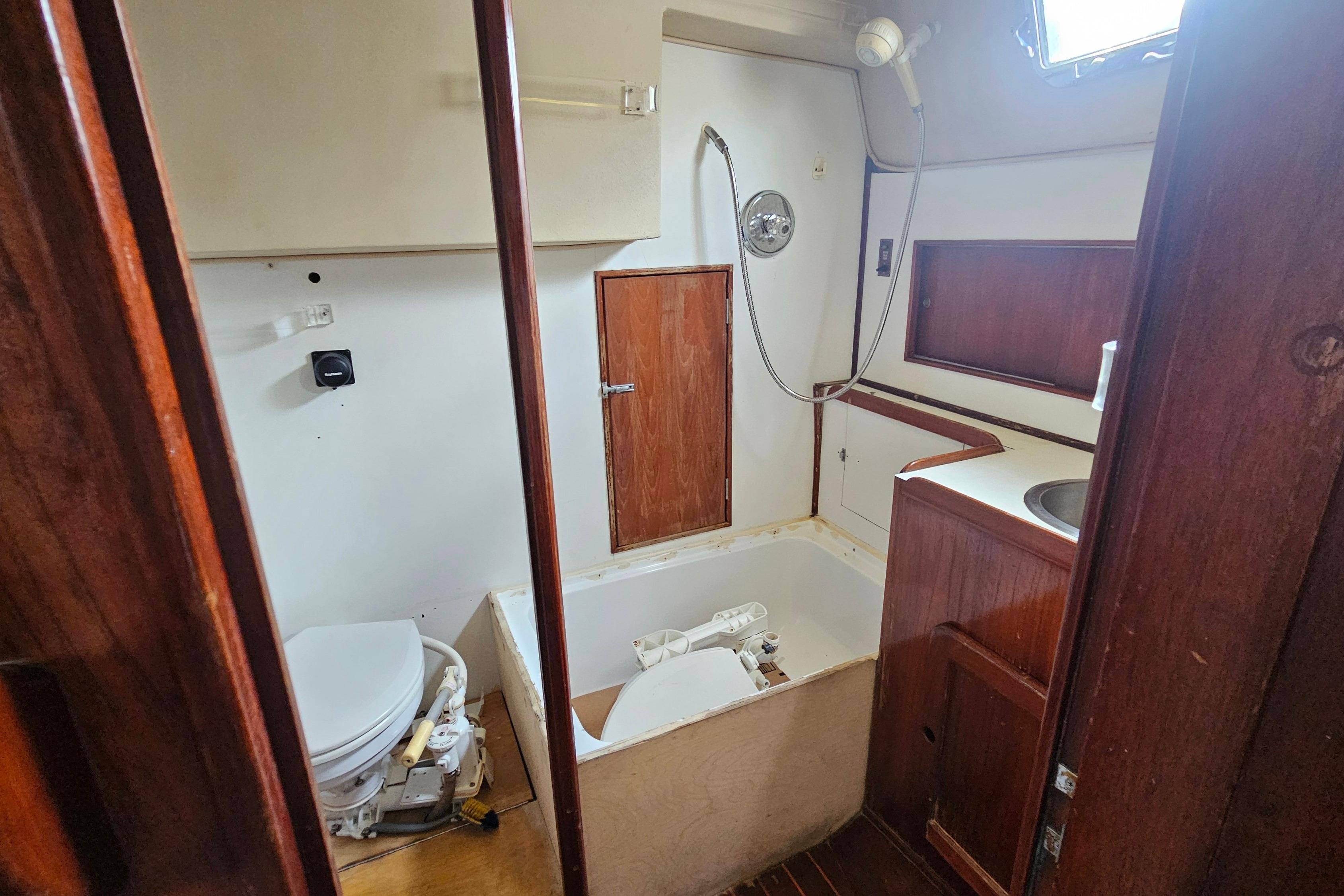 1982 Morgan 462 yacht bathroom with wooden cabinetry, toilet, and shower area.