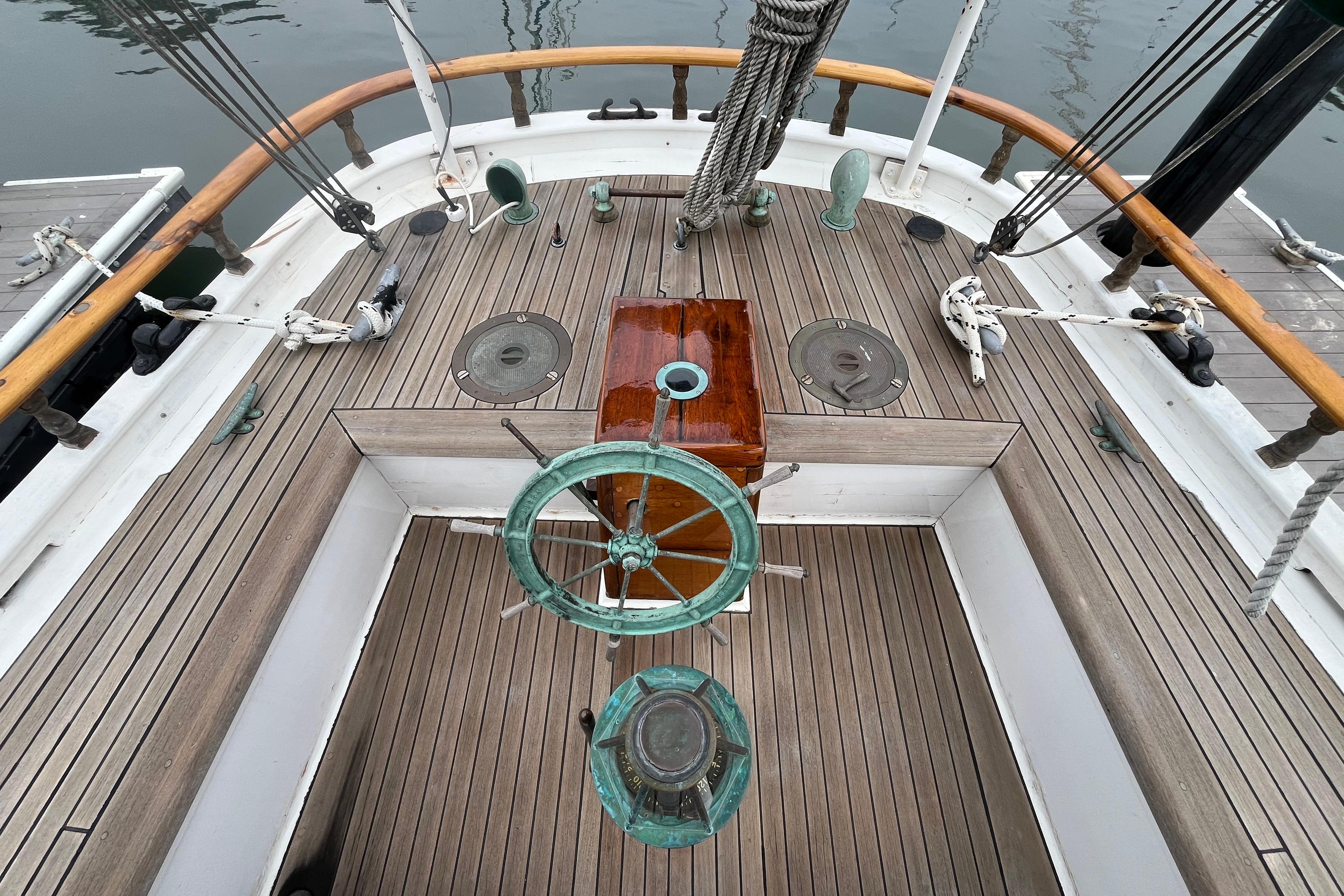 Wooden deck of a 1947 Murray Peterson Schooner with vintage steering wheel.