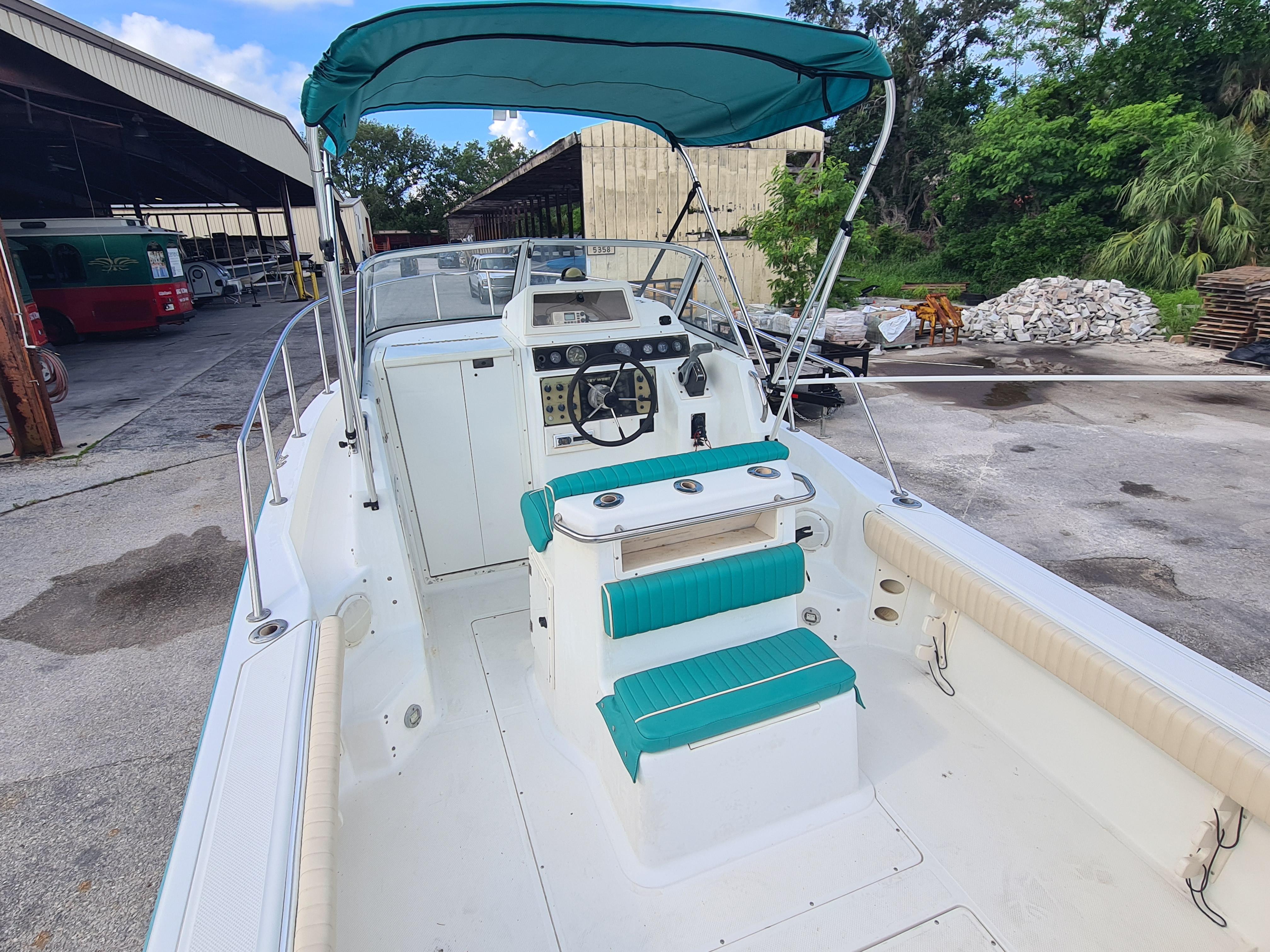 2000 Key West 2300 WA Bluewater boat with teal seating and canopy, docked outdoors.