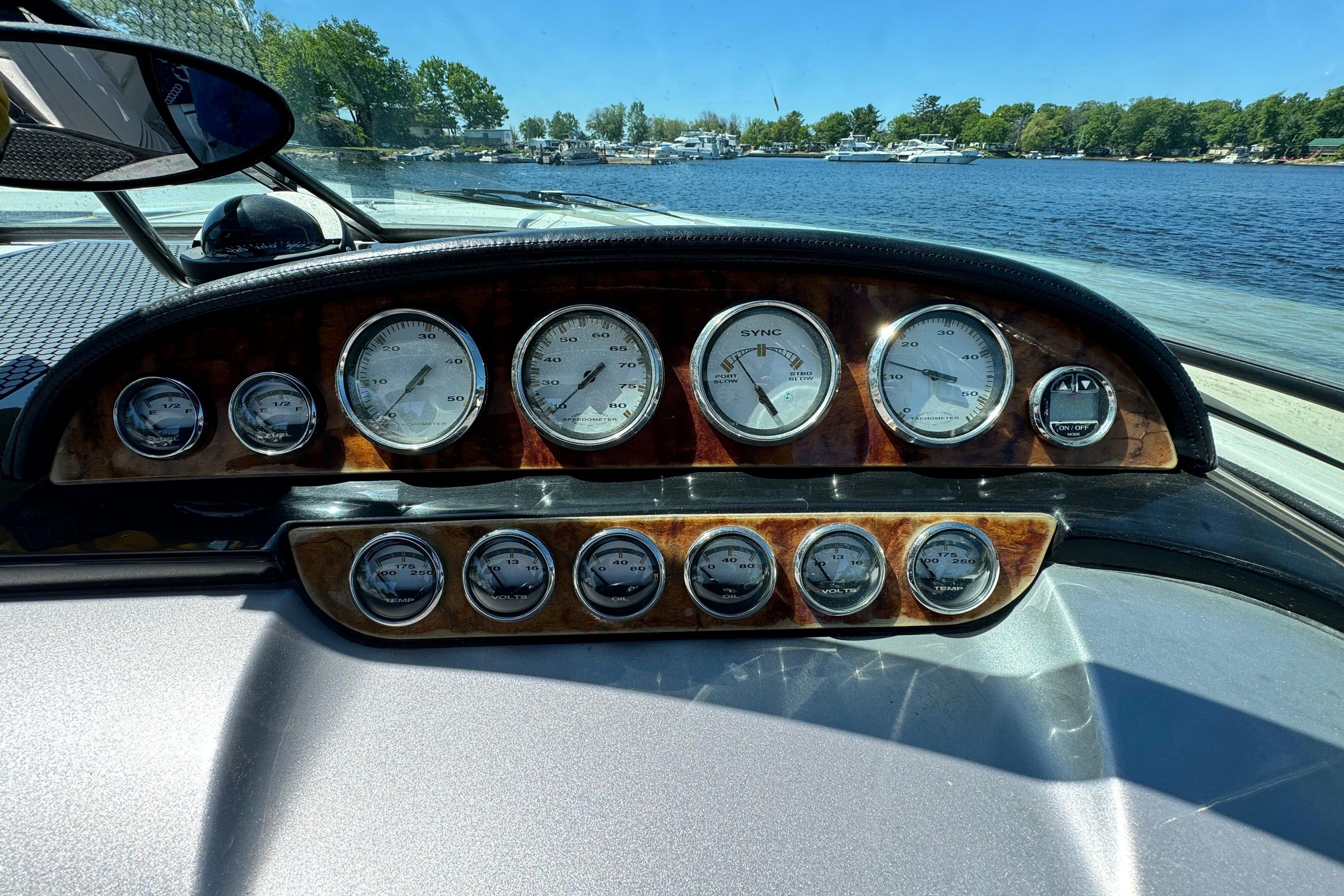 Dashboard of a 2002 Cobalt 360 boat with gauges, overlooking a scenic lake.