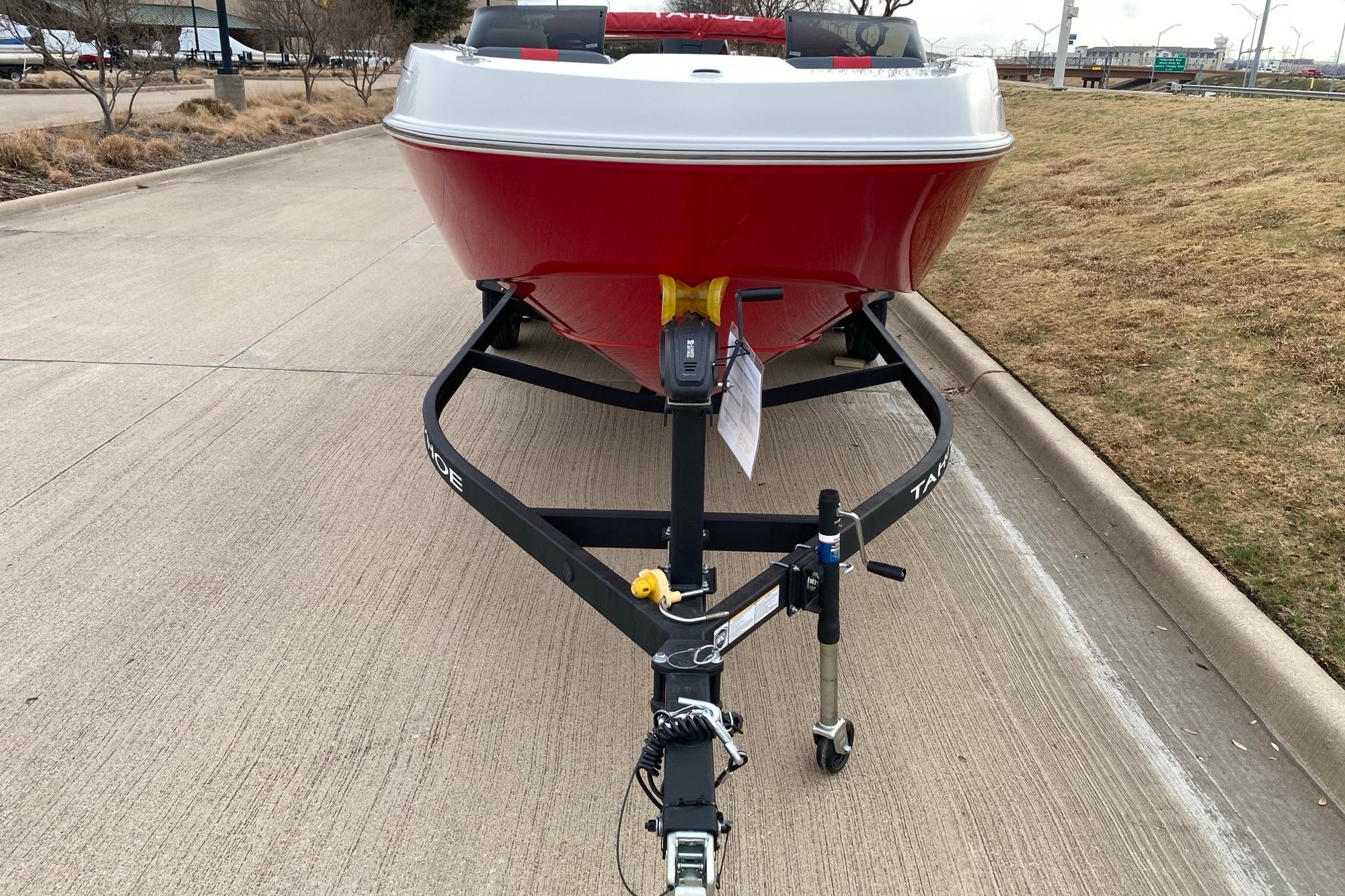 2026 Tahoe T21 boat on trailer, red hull, parked on concrete road.