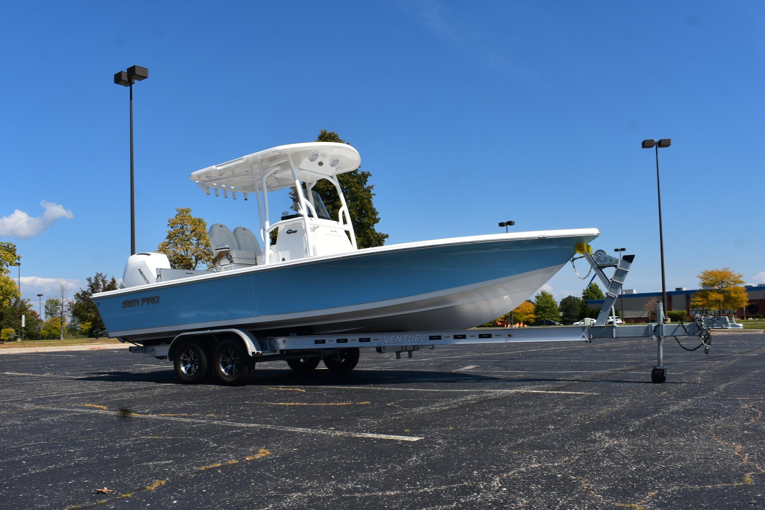 2025 Sea Pro 230 Bay boat on trailer in parking lot under clear blue sky.