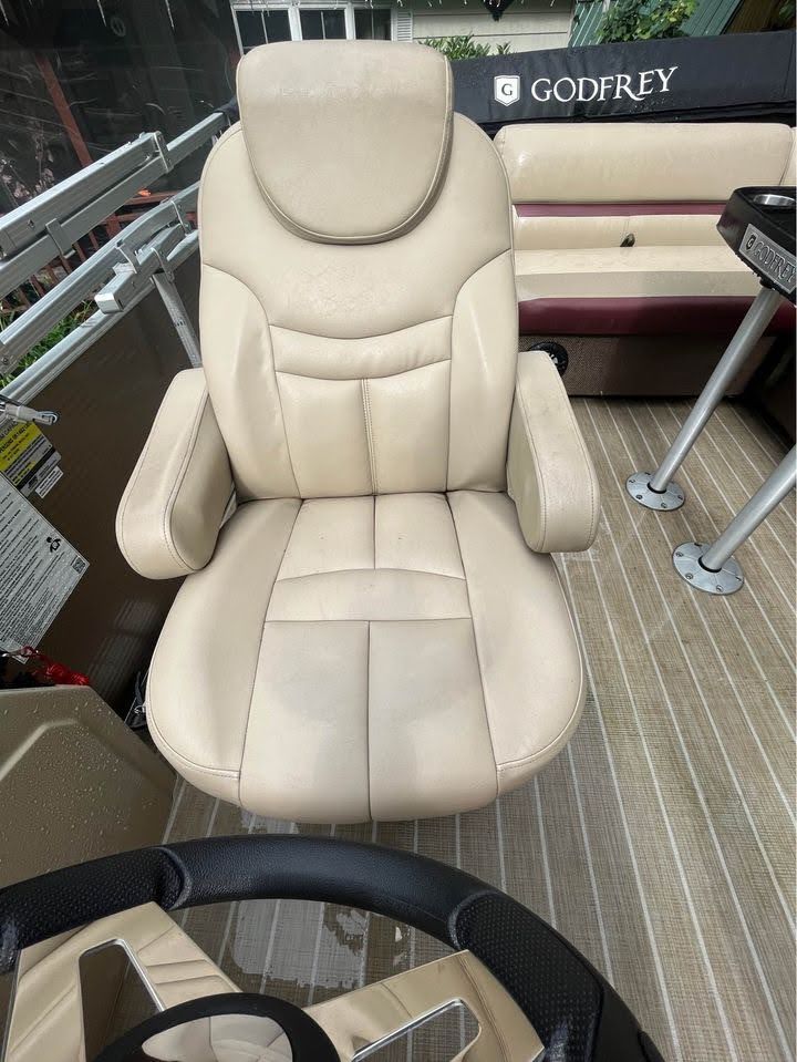 Beige captain's chair on a boat with a steering wheel and Godfrey logo in the background.