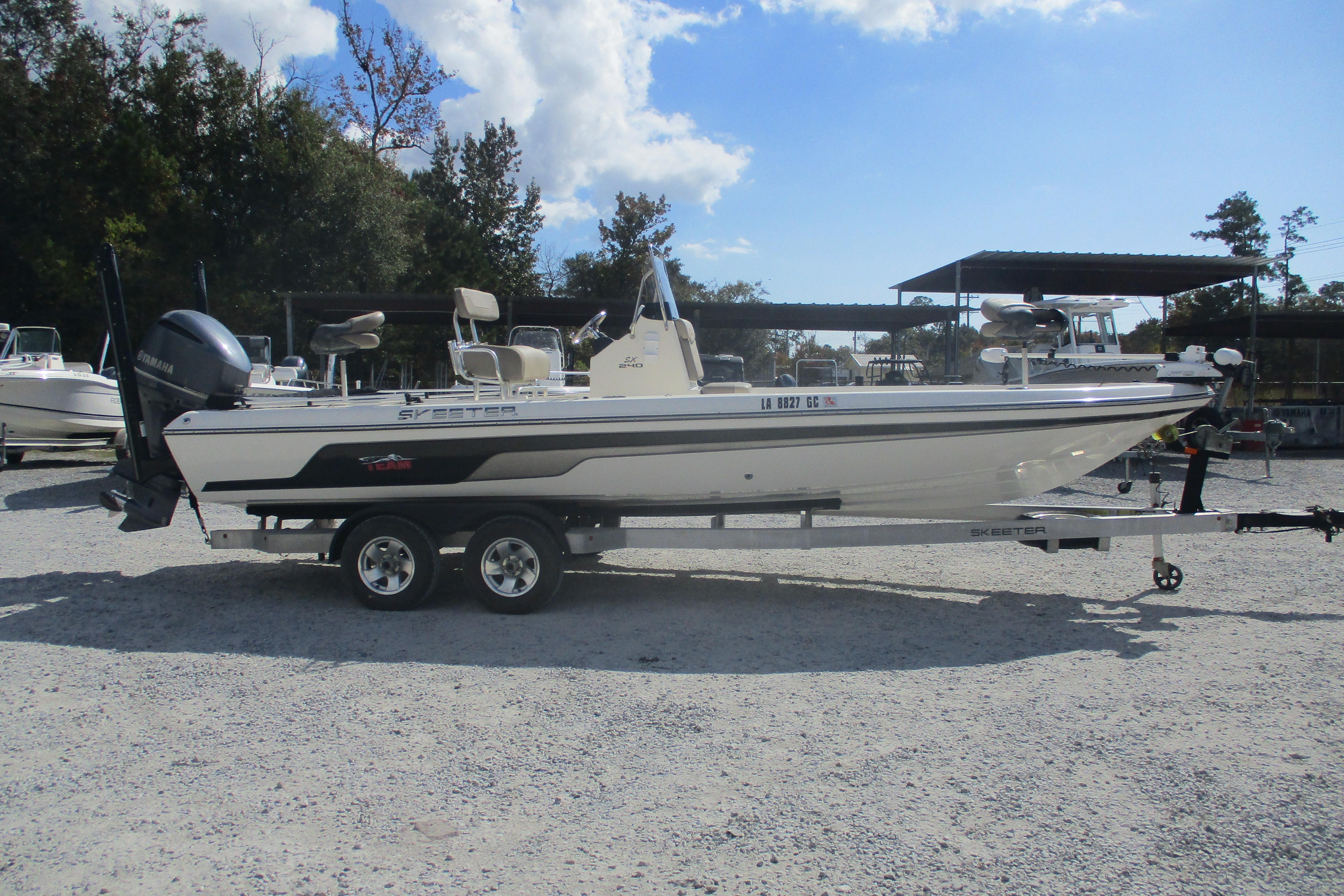 2014 Skeeter SX240 boat on trailer in outdoor lot, clear sky background.