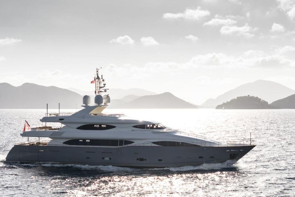 Luxurious 2009 CRN 129 yacht cruising on serene waters with scenic mountain backdrop.