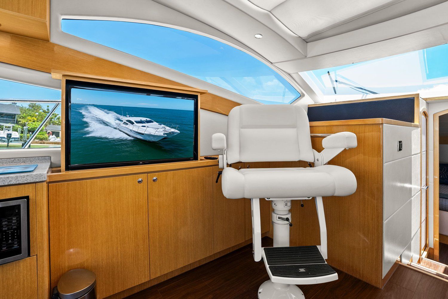 Interior of a modern yacht with a white captain's chair and built-in television.