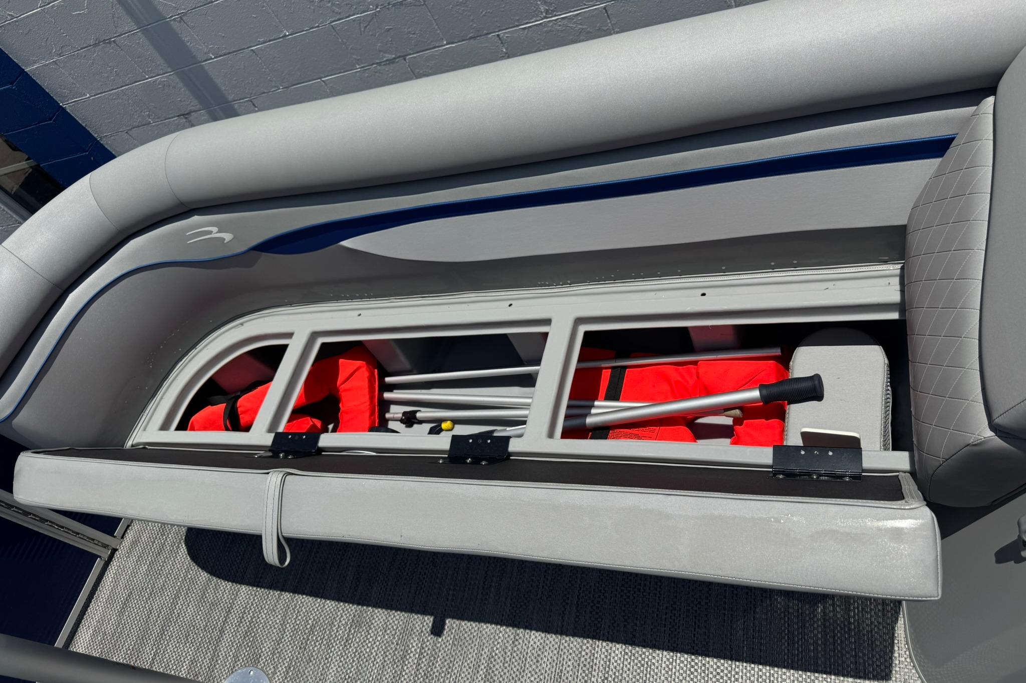2024 Bennington SV 168 SLV boat storage compartment with life jackets and paddle.
