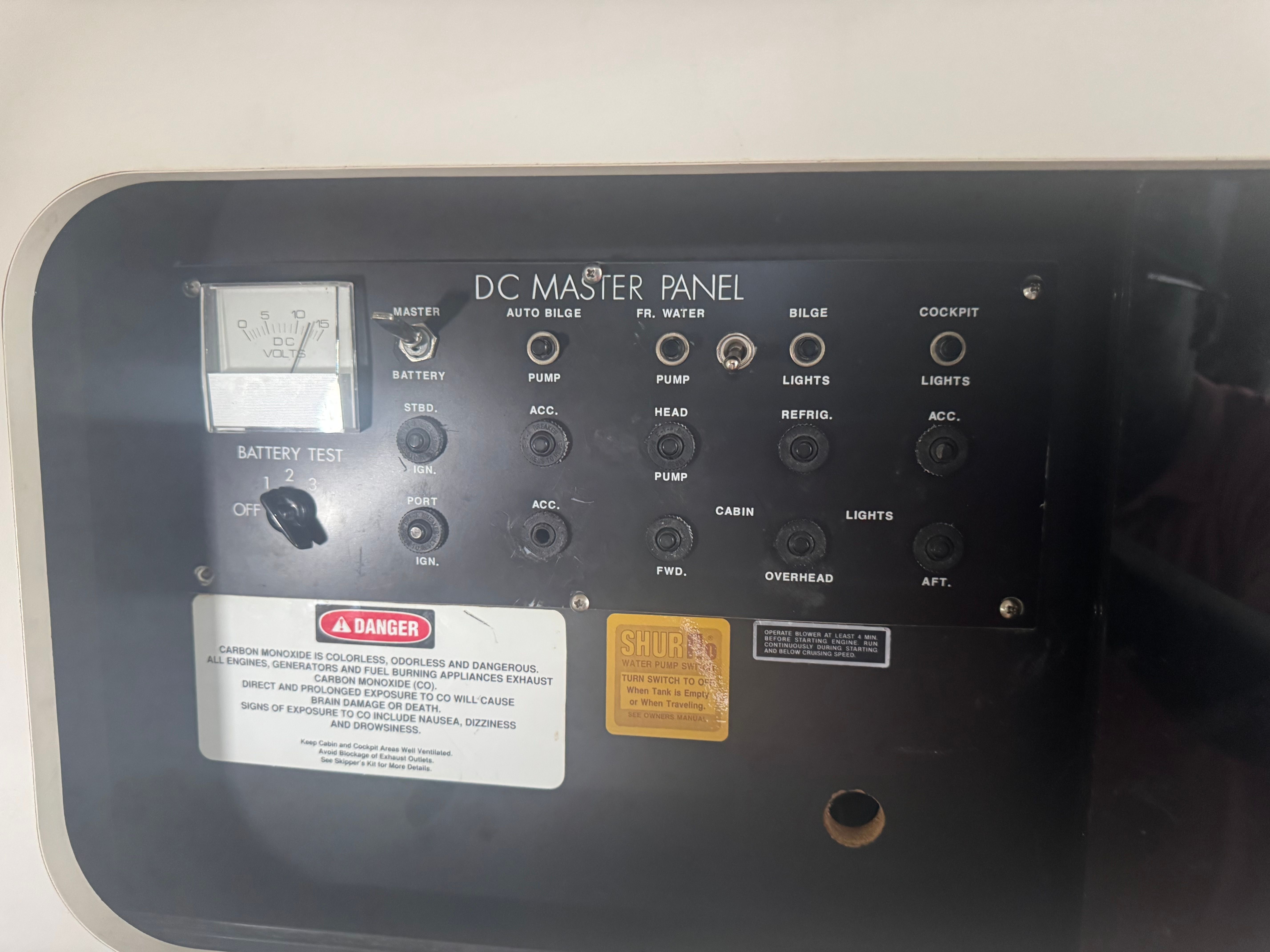 The image shows a DC master panel with various switches and indicators for boat functions.