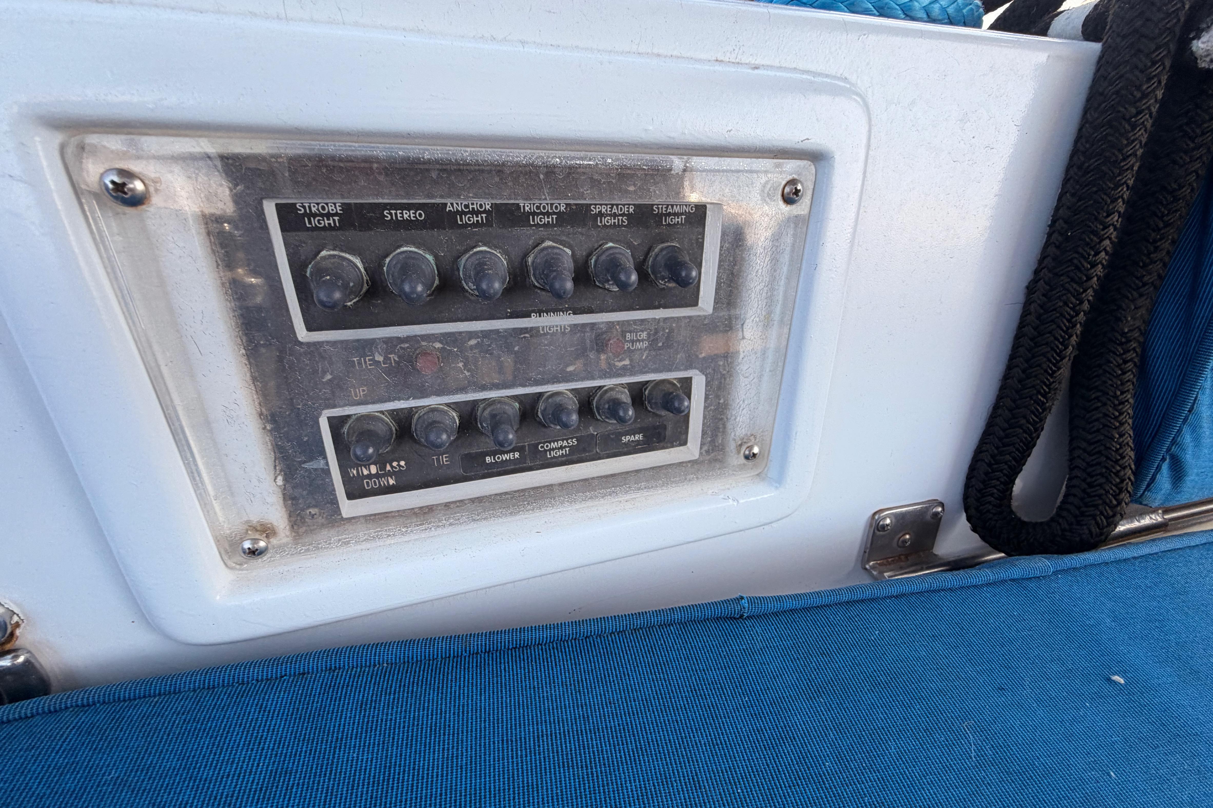 Control panel on a 1991 Hylas 51 yacht with various switches and blue seating.