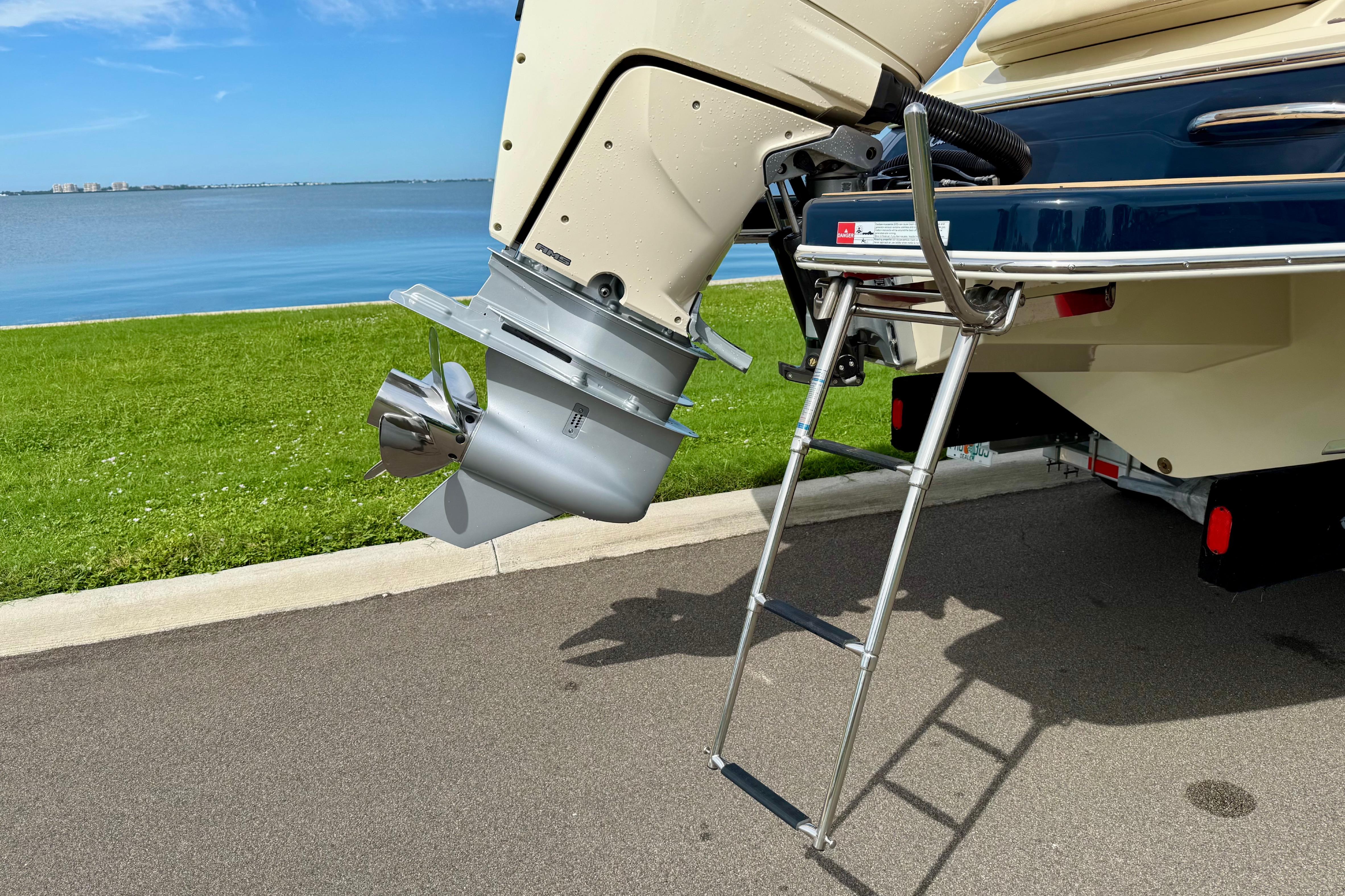 2026 Chris-Craft Sportster 28 boat with outboard motor and ladder by a lakeside.