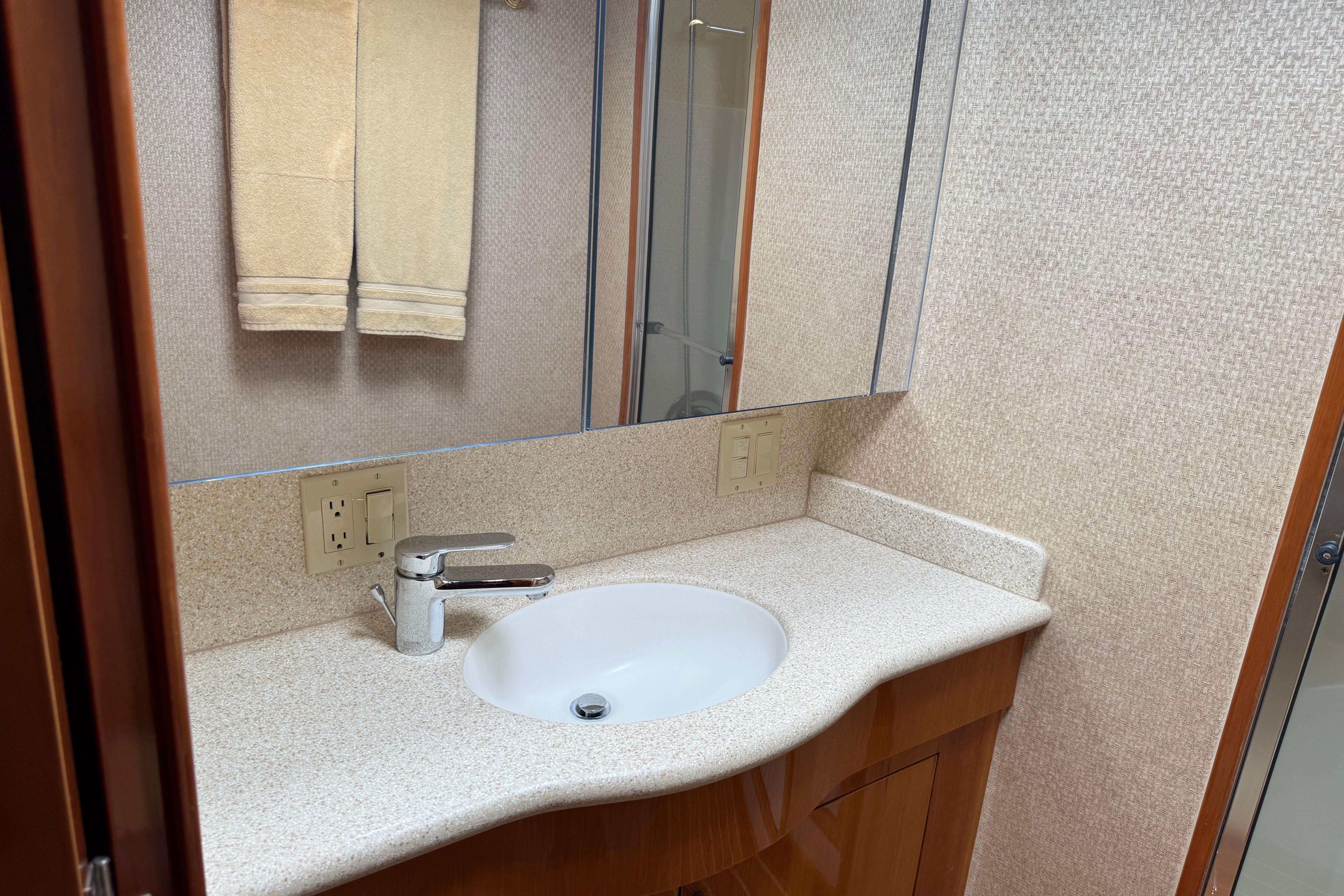 Bathroom vanity with sink and mirror in 2004 Hatteras 60 Convertible yacht.
