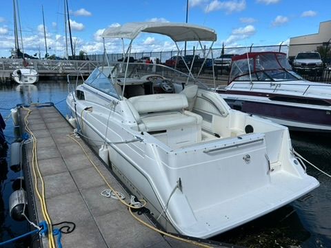 A 1997 Bayliner 2566 Ciera docked. It features an open cockpit and a canopy.