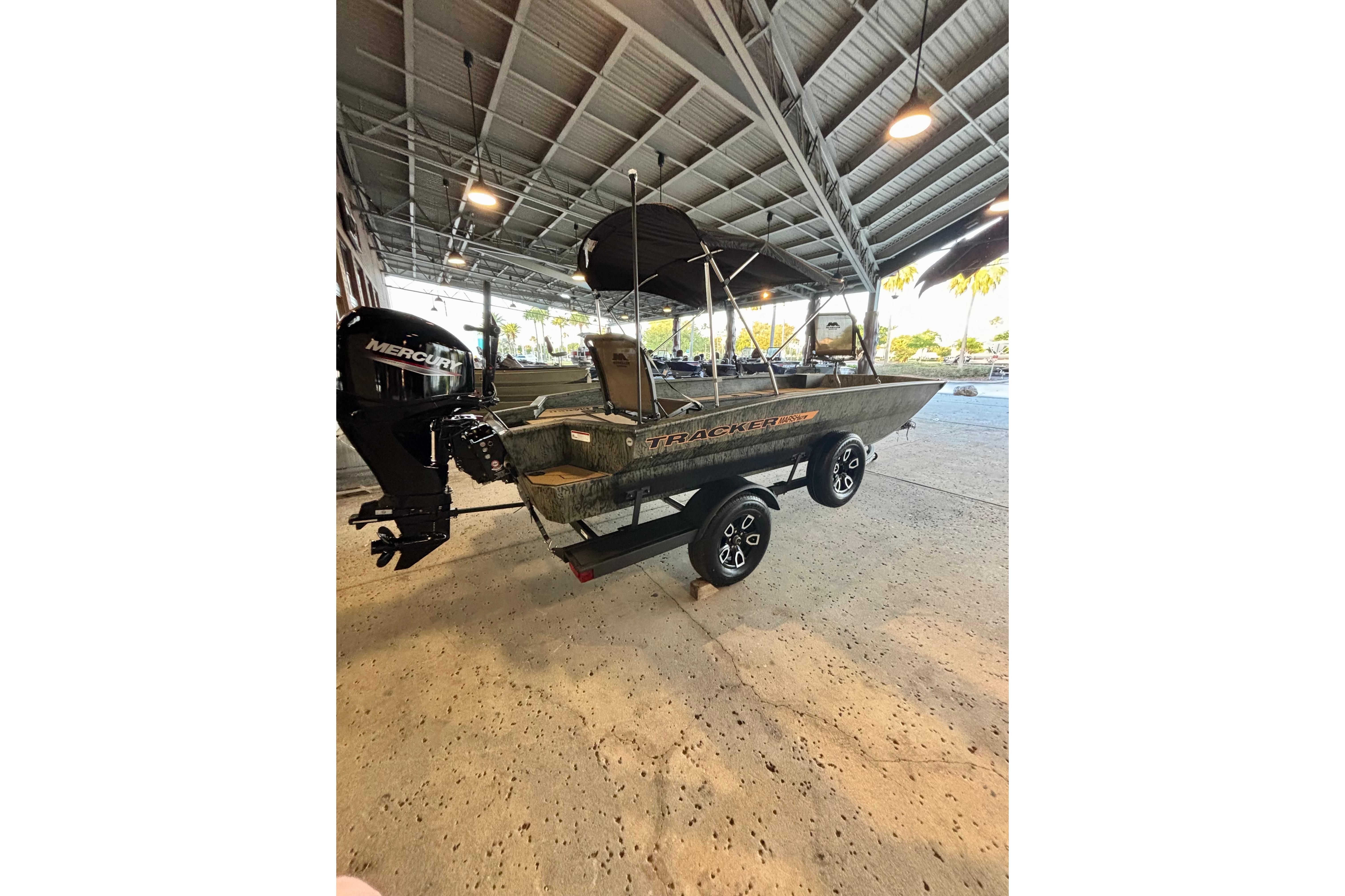 2026 Tracker Grizzly 1756 T Marsh boat with Mercury engine on trailer in covered area.