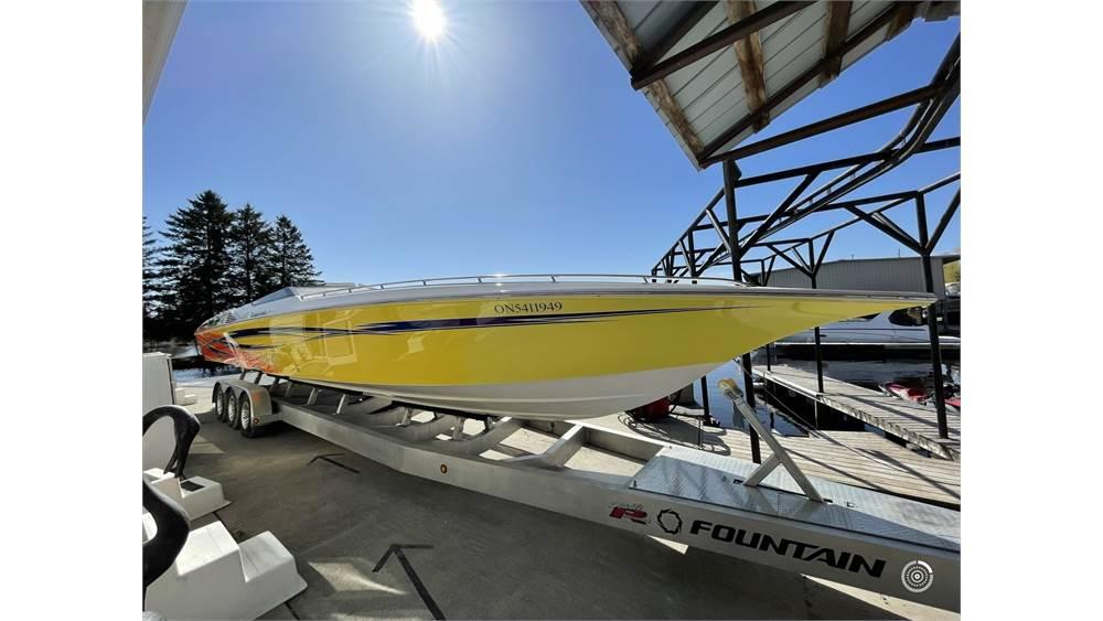Yellow 2006 Fountain 42 speedboat on trailer under clear blue sky.