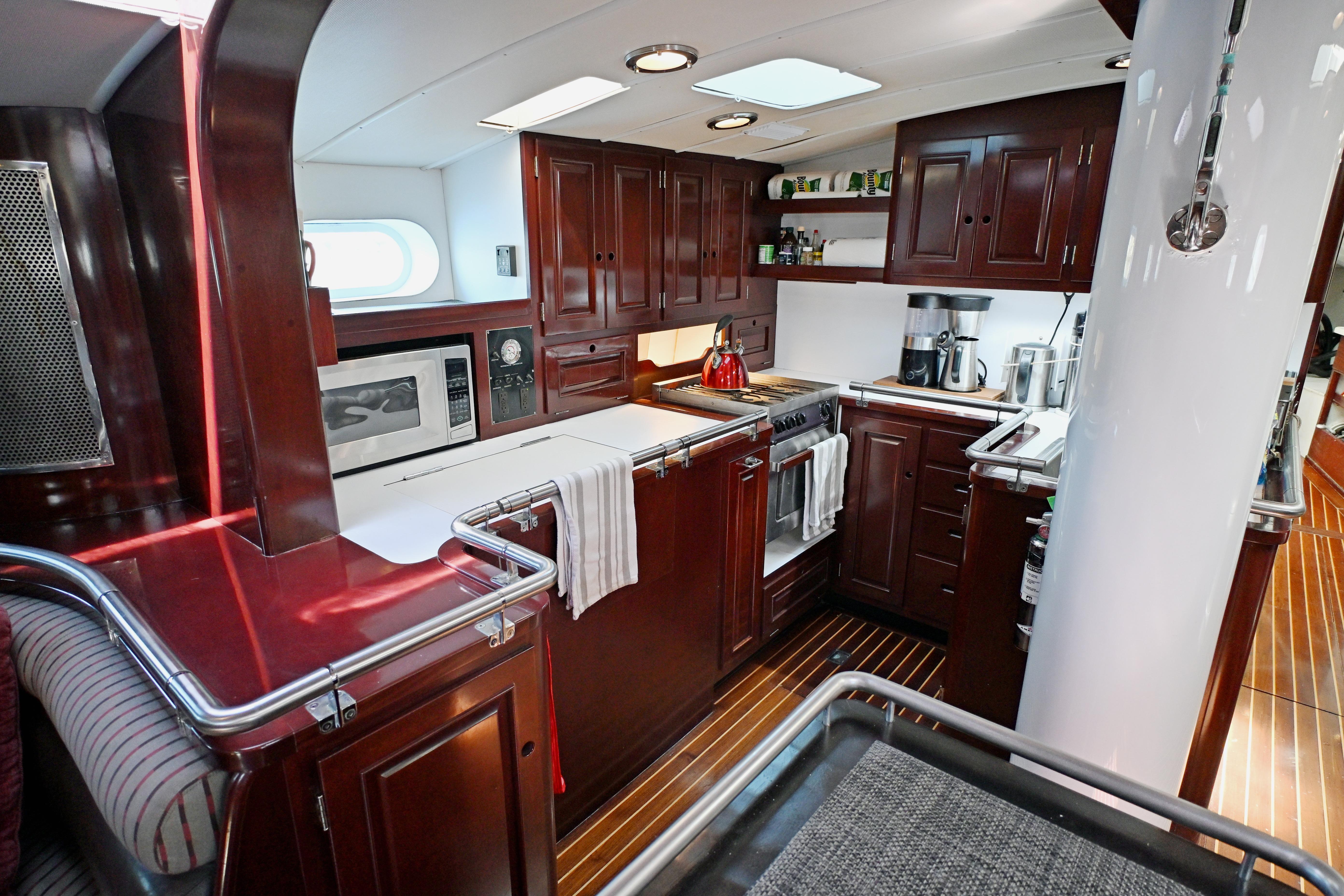Luxurious wooden yacht kitchen interior, Abeking & Rasmussen Tripp 74, 1968 model, featuring modern appliances.