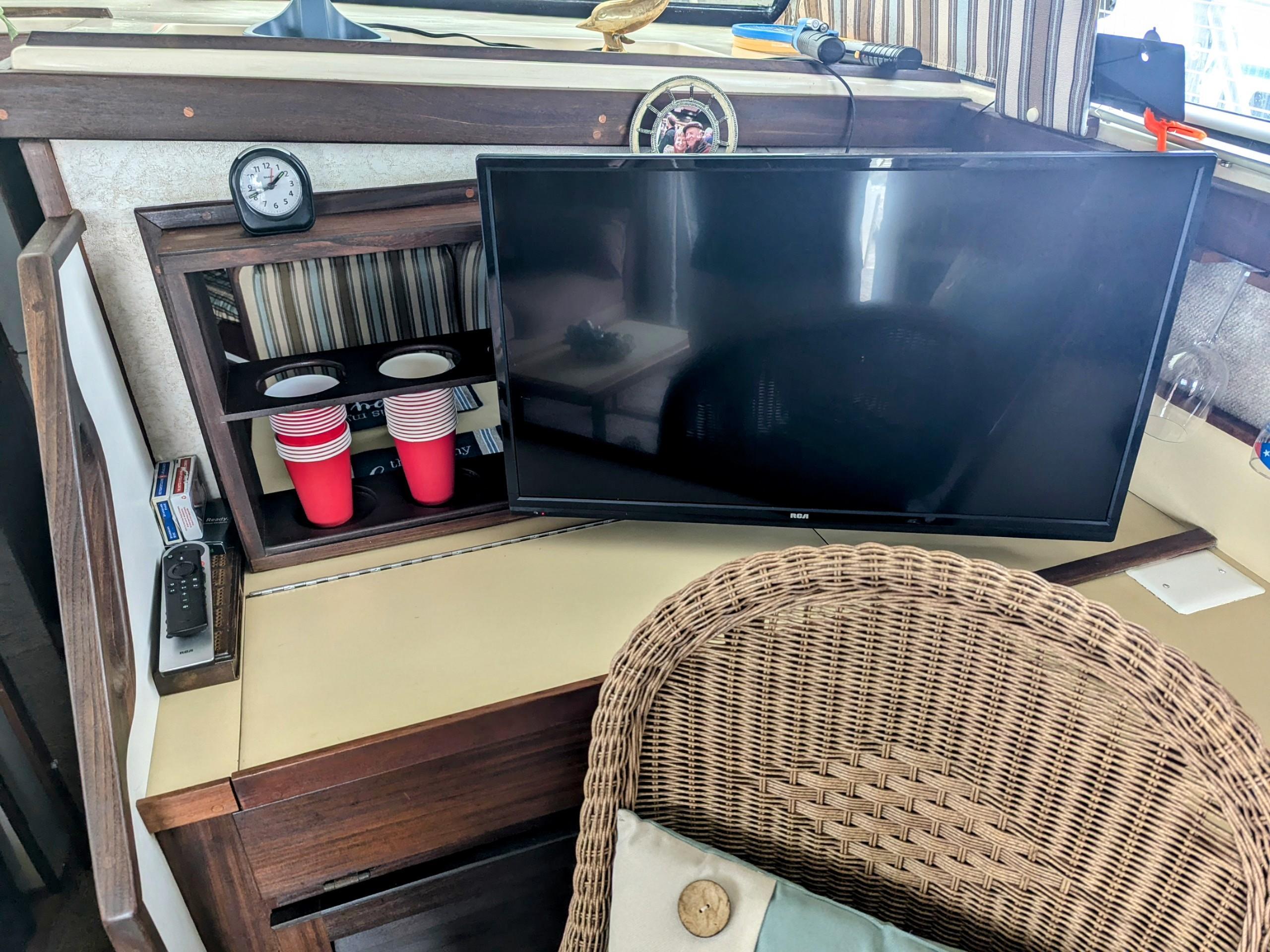 1981 Silverton 37 Convertible interior with TV, wicker chair, and red cups on a shelf.