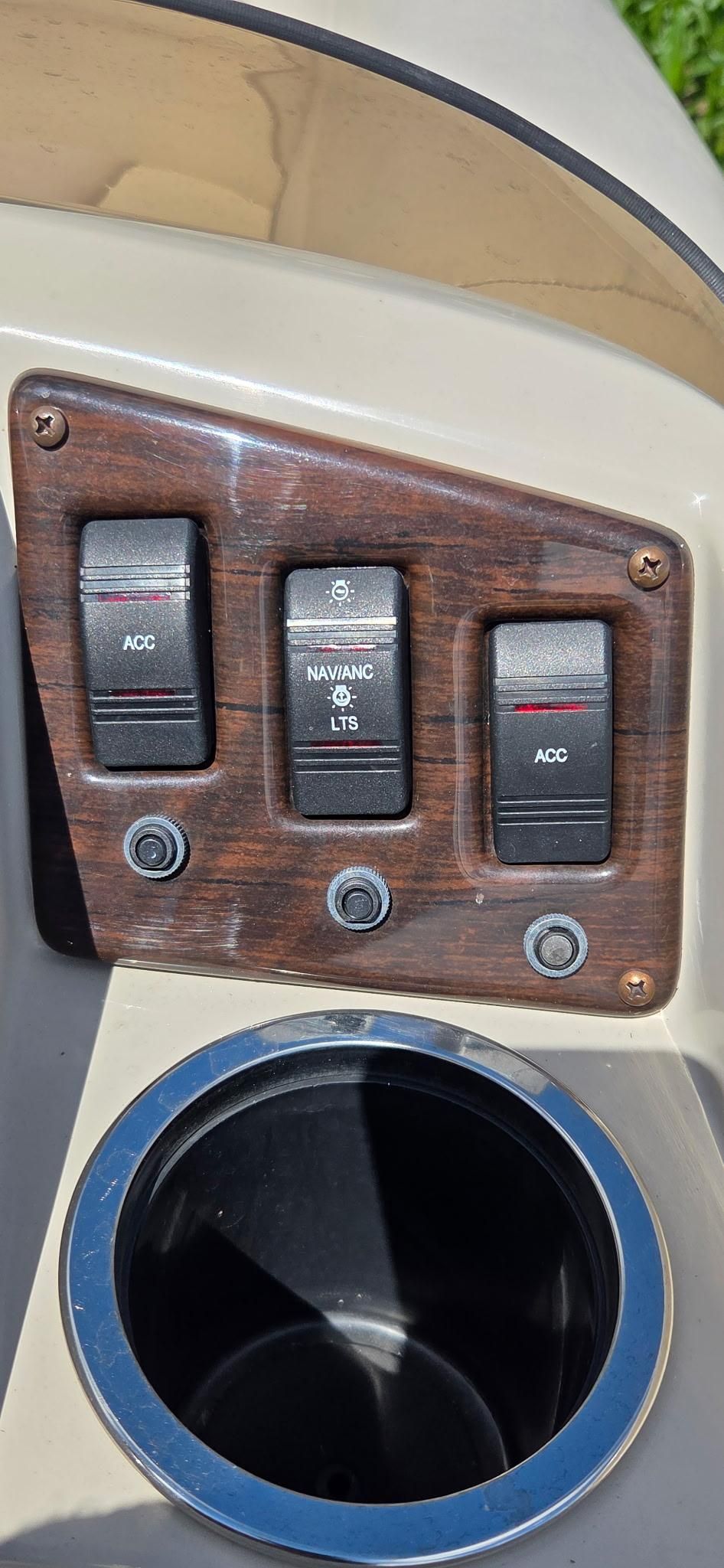 Close-up of a boat control panel with three switches and a cup holder.